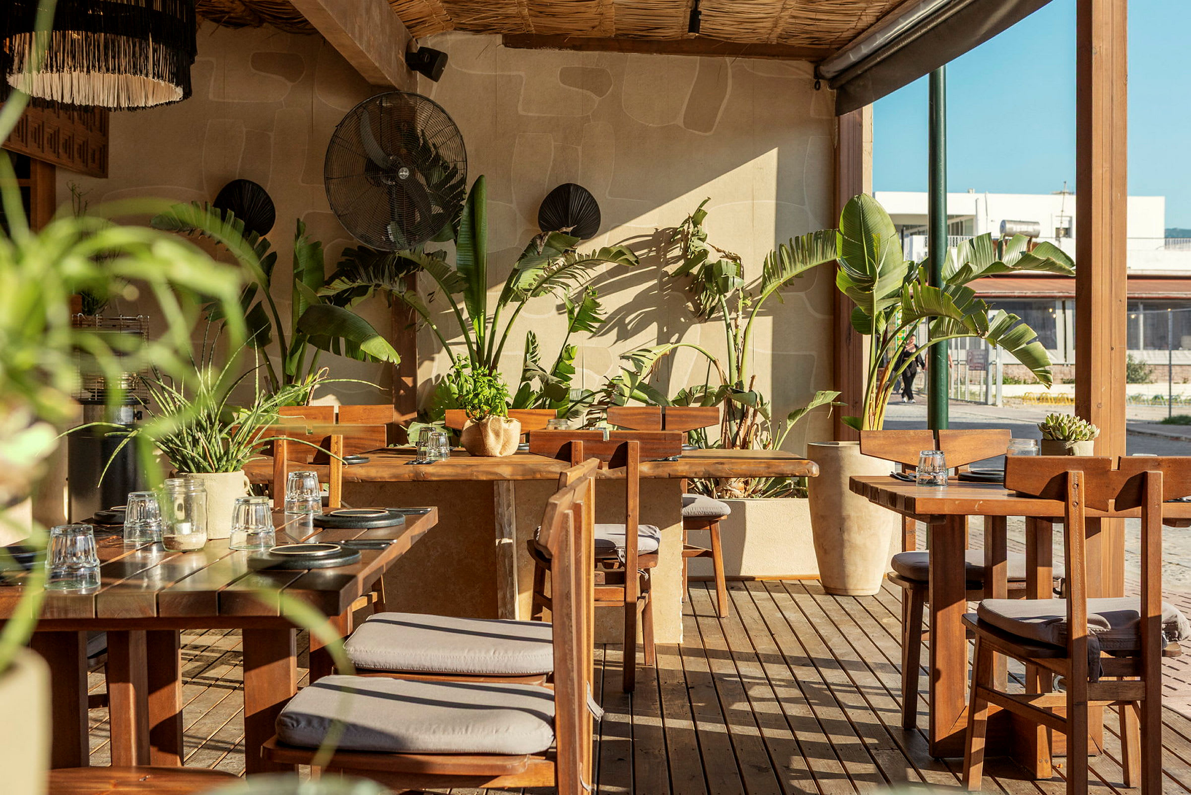 En udendørsrestaurant med træmøbler og grønne planter. (AI-genereret tekst)