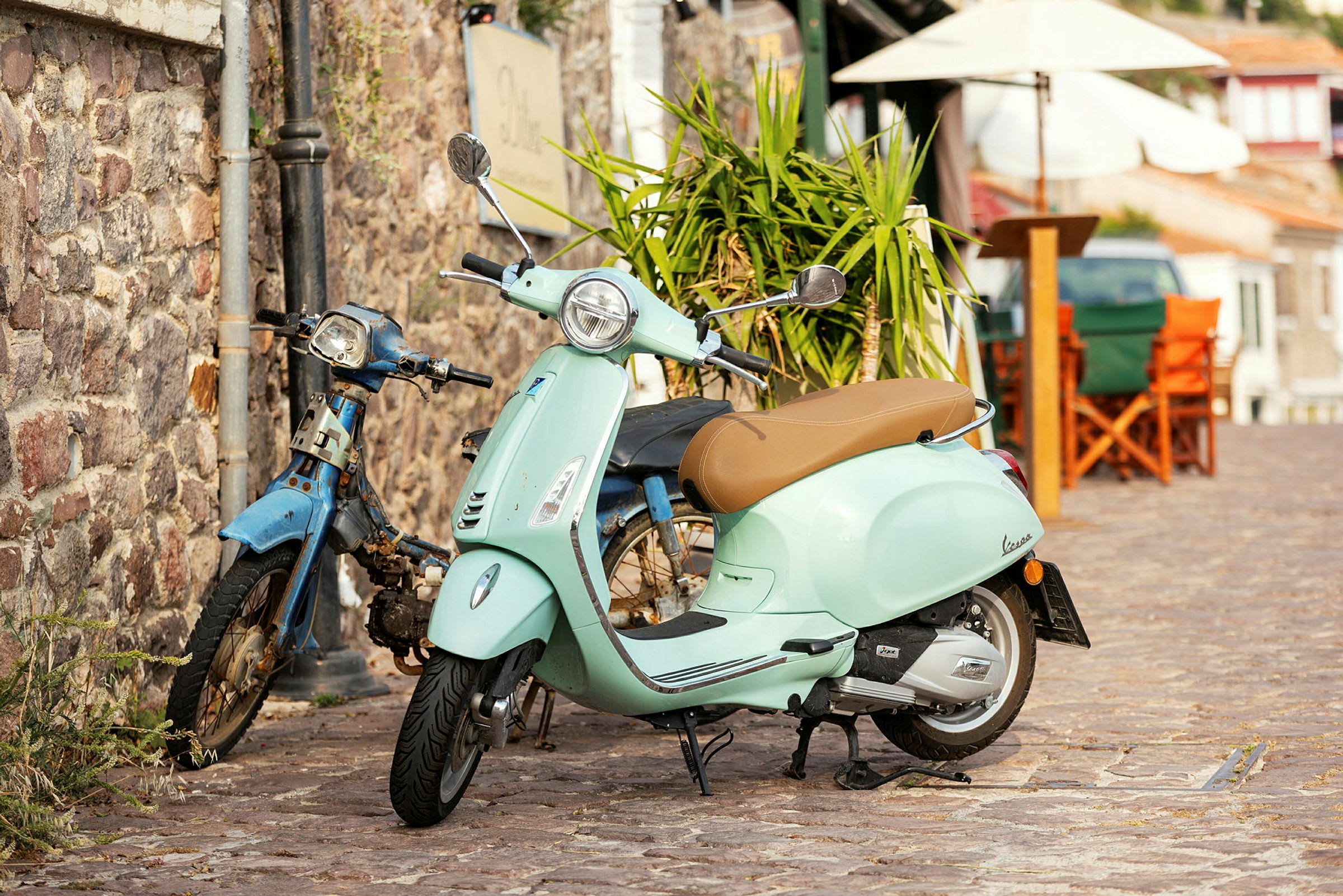 En lysegrøn scooter parkeret ved siden af en gammel blå knallert. (AI-genereret tekst)