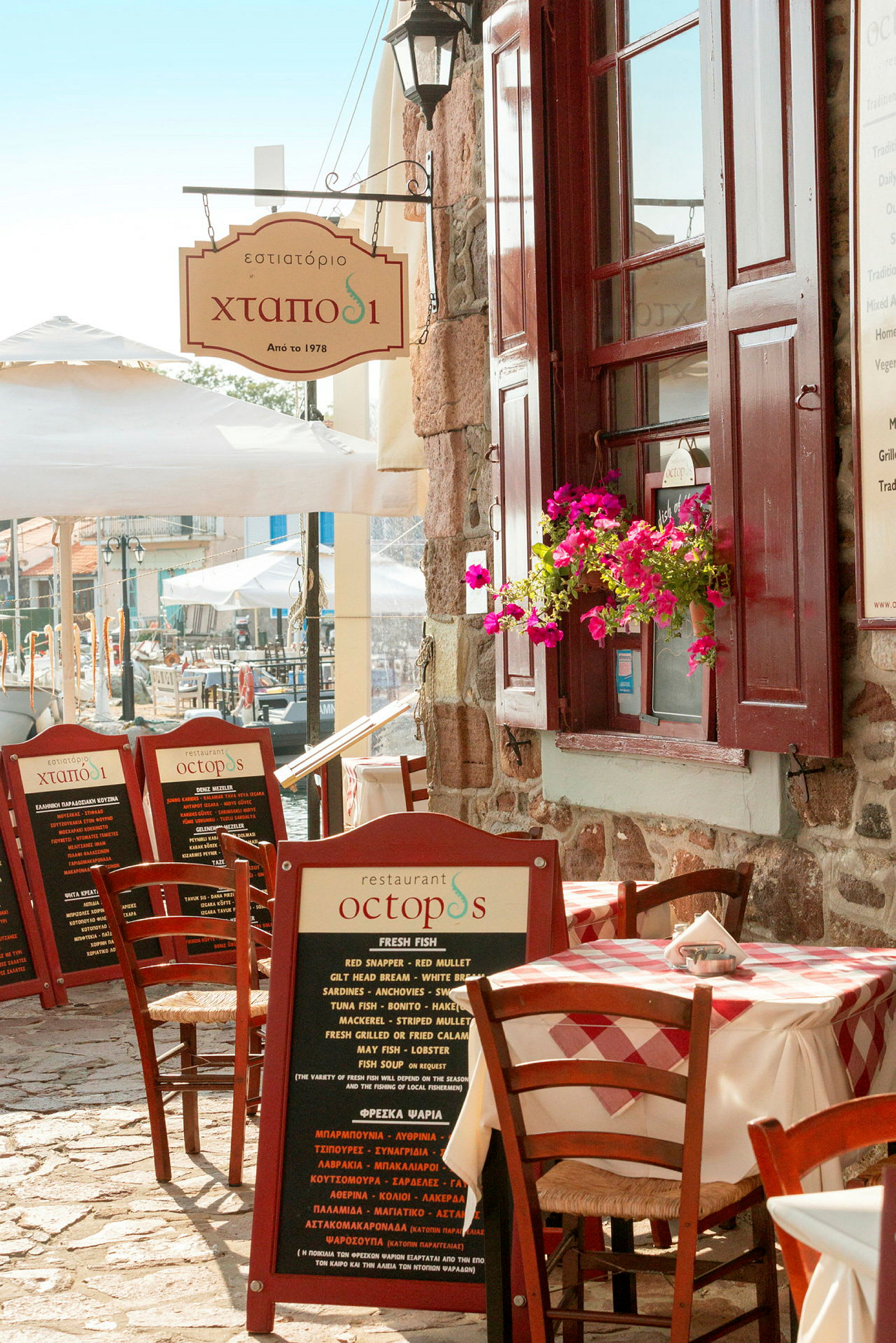 Eksteriør af en restaurant med udendørs servering og et skilt med teksten 'Octopus'. (AI-genereret tekst)
