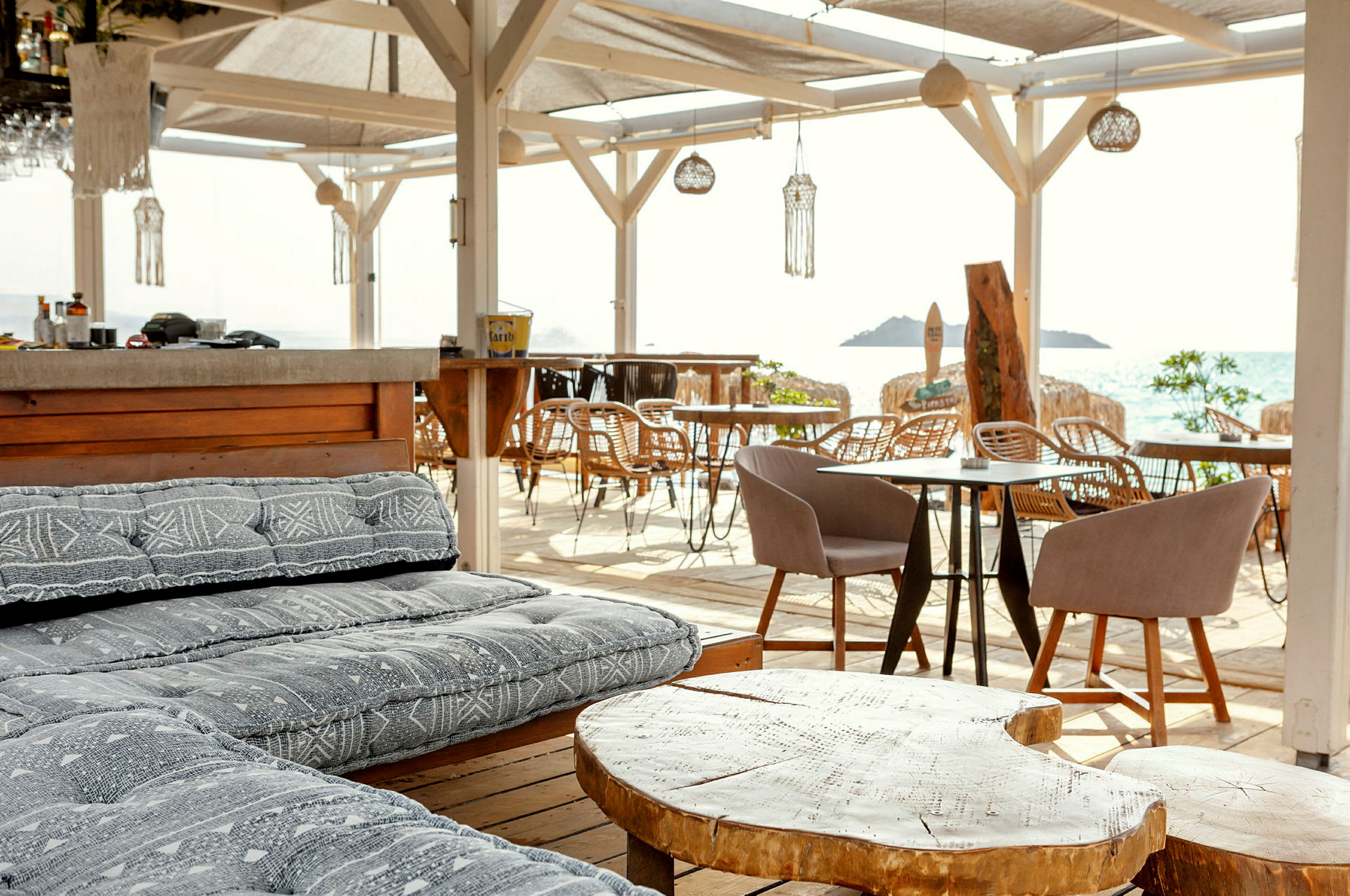 En strandbar med komfortable siddepladser, træborde og udsigt over havet. (AI-genereret tekst)