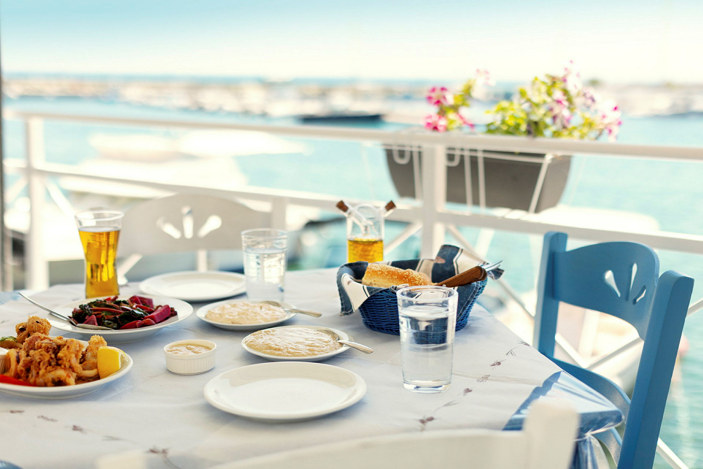 Et dækket bord med mad og drikke på en terrasse med udsigt over havet. (AI-genereret tekst)