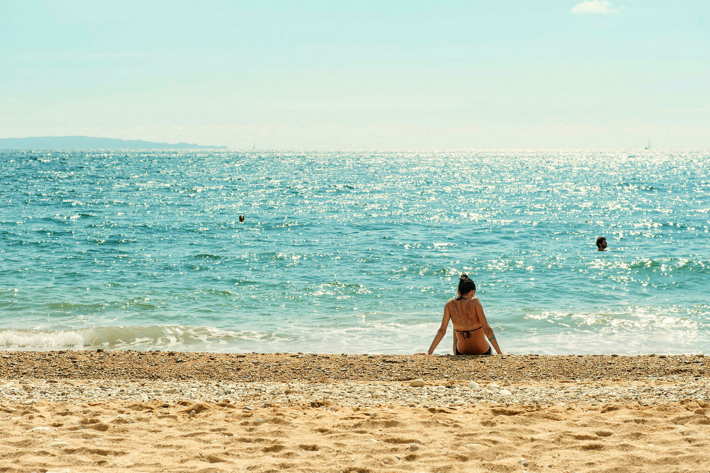 En person sidder på stranden med havet i baggrunden. (AI-genereret tekst)