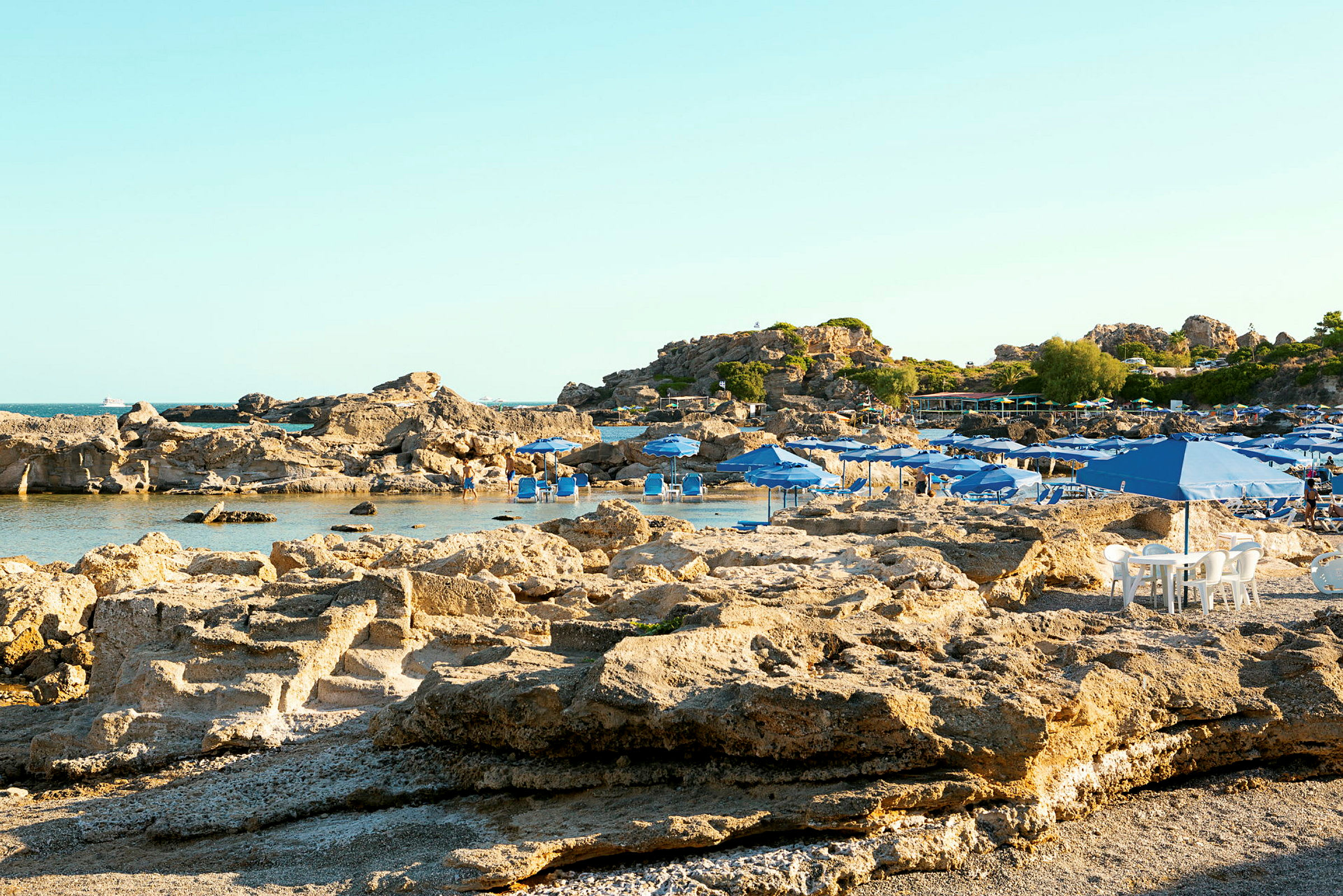 Klippestrand med blå parasoller. (AI-genereret tekst)