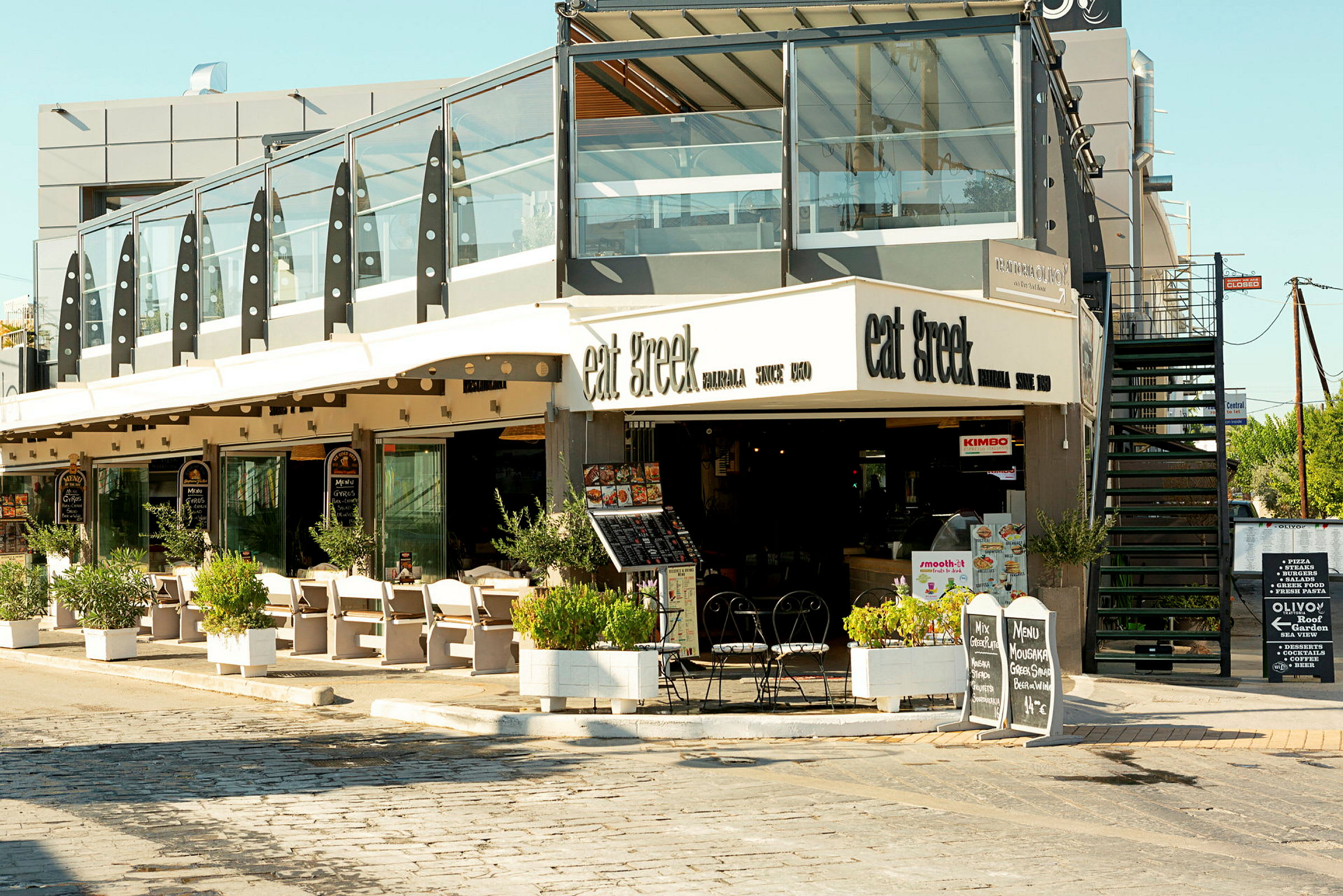 Restaurant med udendørs servering og skilte, der viser menuen. (AI-genereret tekst)