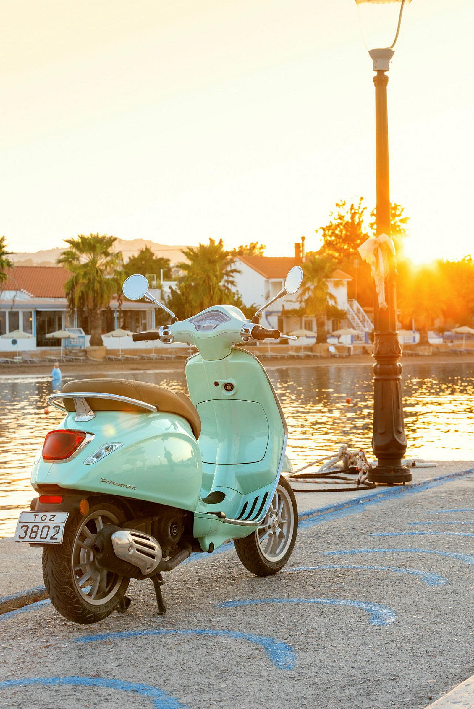 En lysegrøn scooter ved en kaj om aftenen med solnedgangen. (AI-genereret tekst)