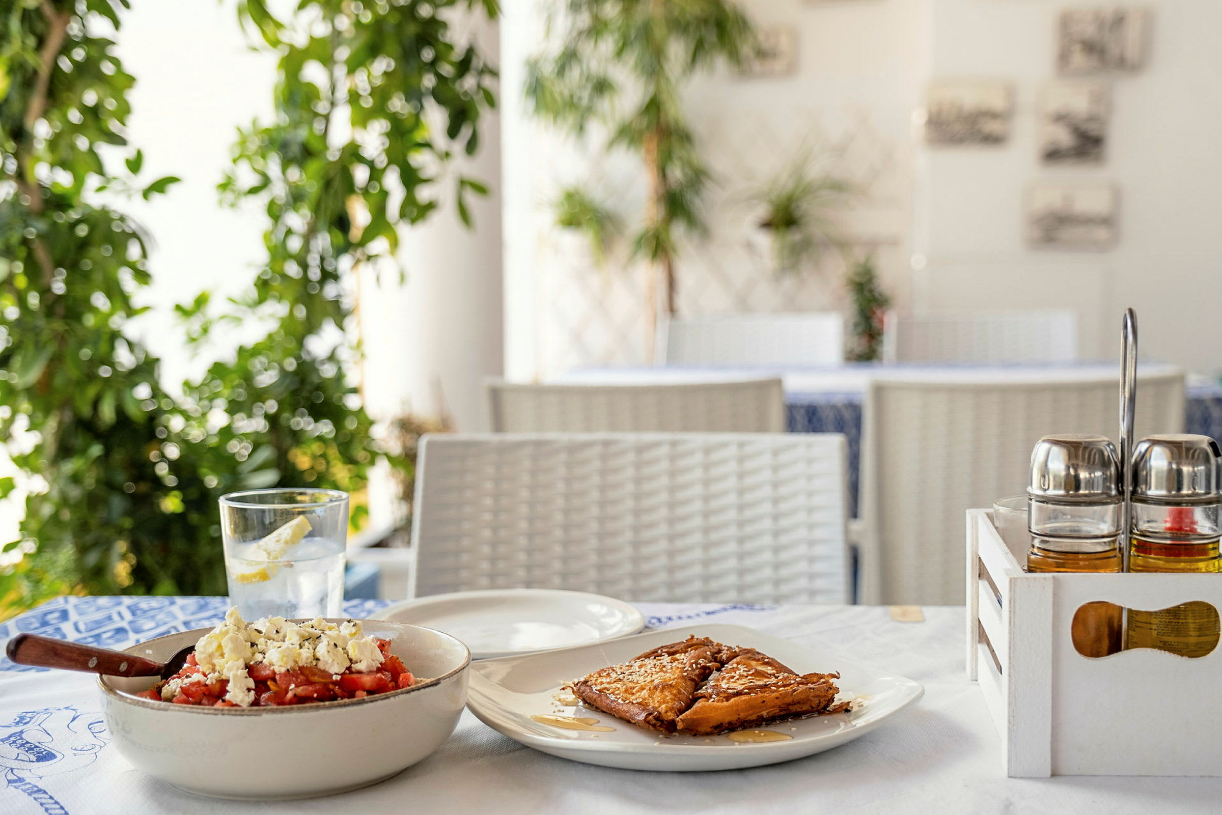 Et nærbillede af et restaurantbord med en traditionel græsk ret og dessert. (AI-genereret tekst)