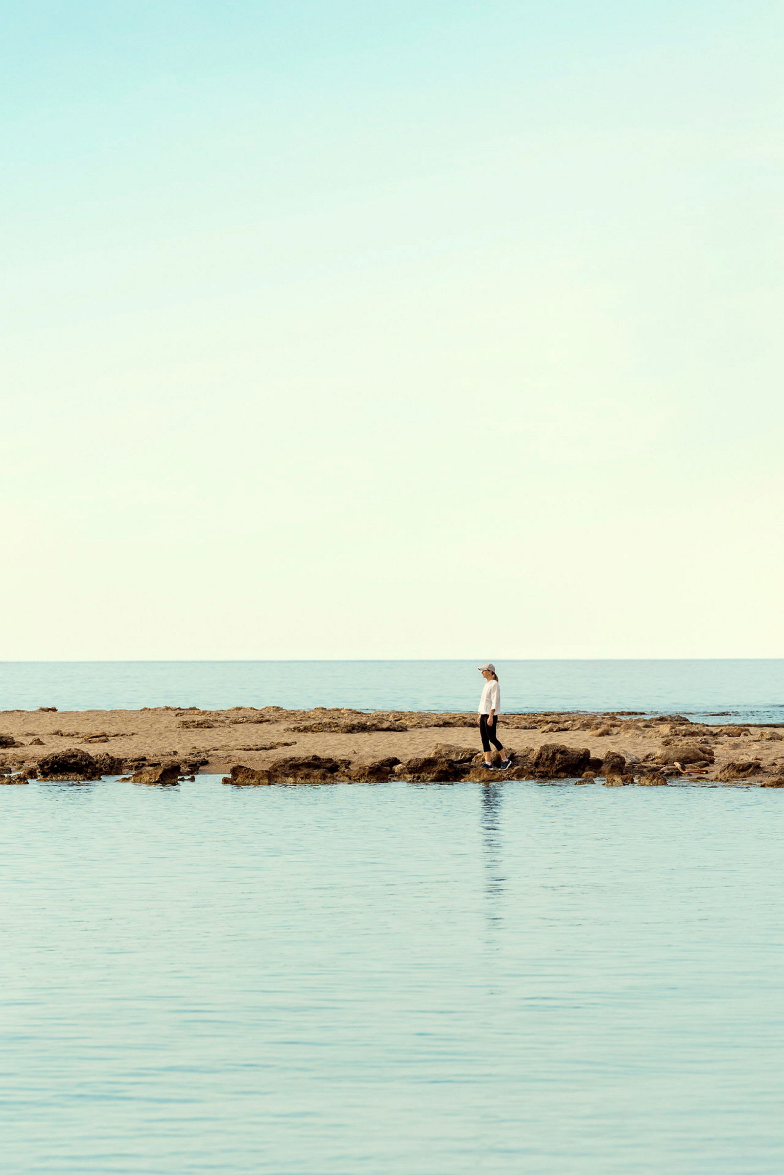 Person står på klippefyldt strand ved havet. (AI-genereret tekst)