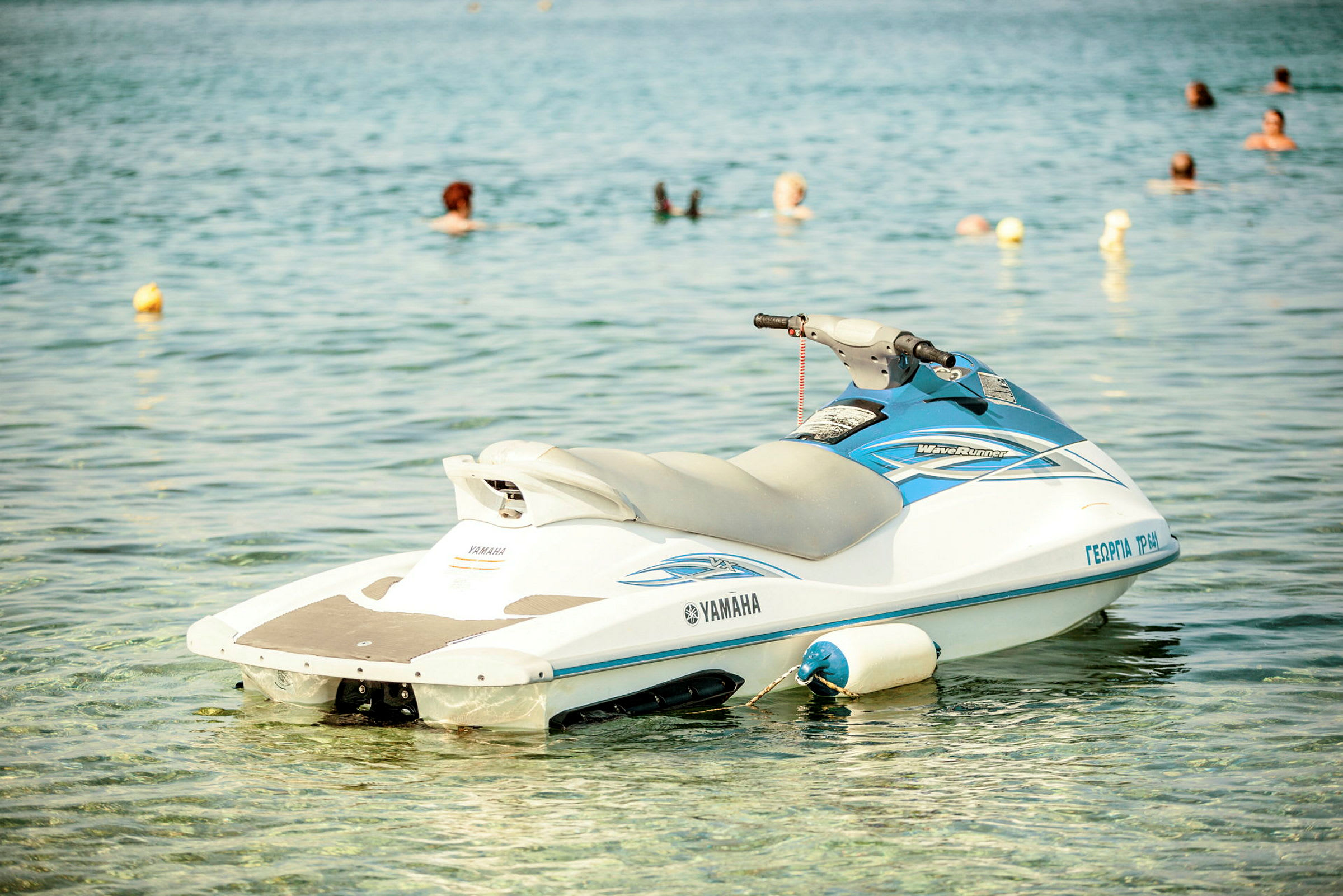 En jetski flyder på vandet med svømmende personer i baggrunden. (AI-genereret tekst)