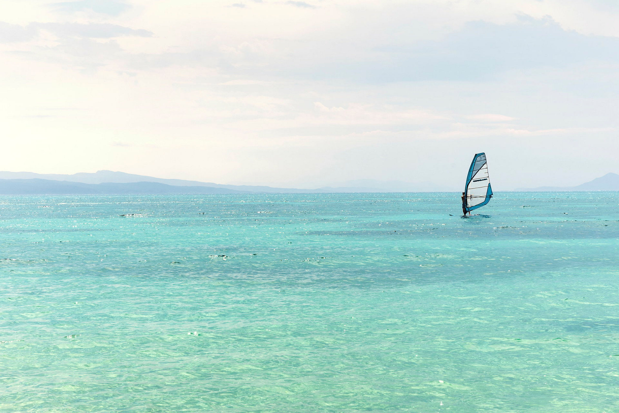 En person windsurfer på en klar blå havoverflade. (AI-genereret tekst)