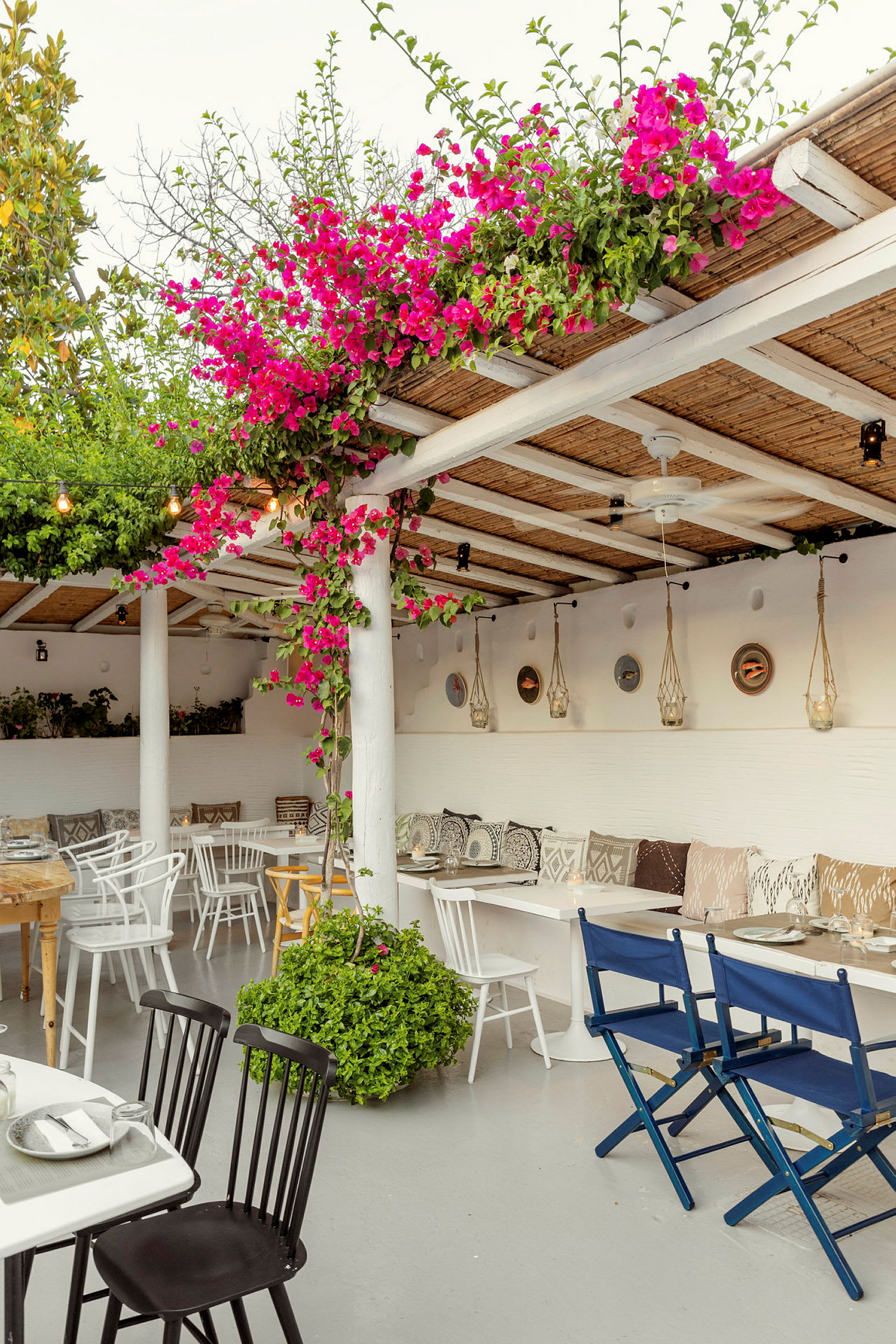 En terrasse med siddepladser, farverige blomster og hængende dekorationer. (AI-genereret tekst)