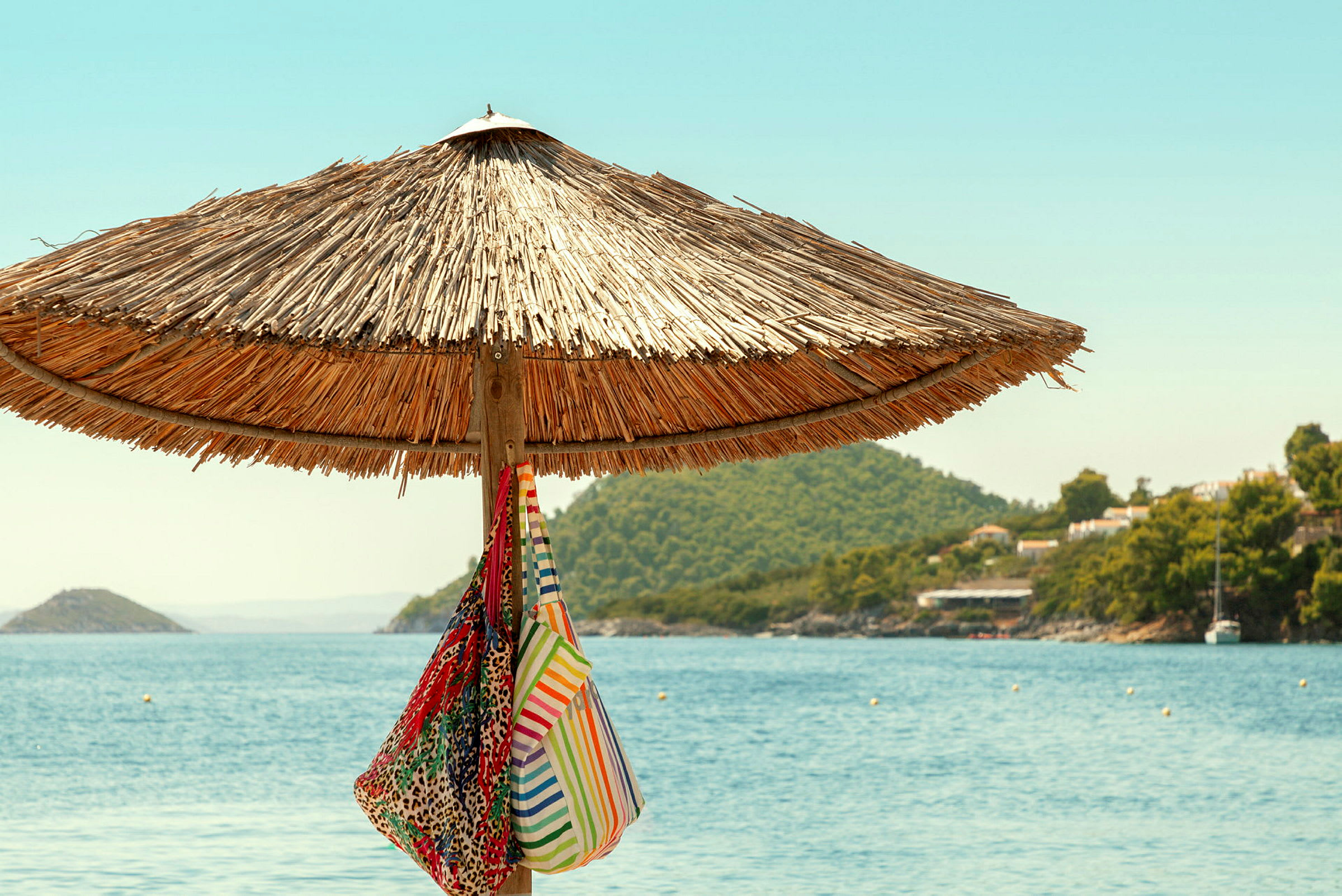 En parasol af siv på en strand med to tasker hængende. (AI-genereret tekst)