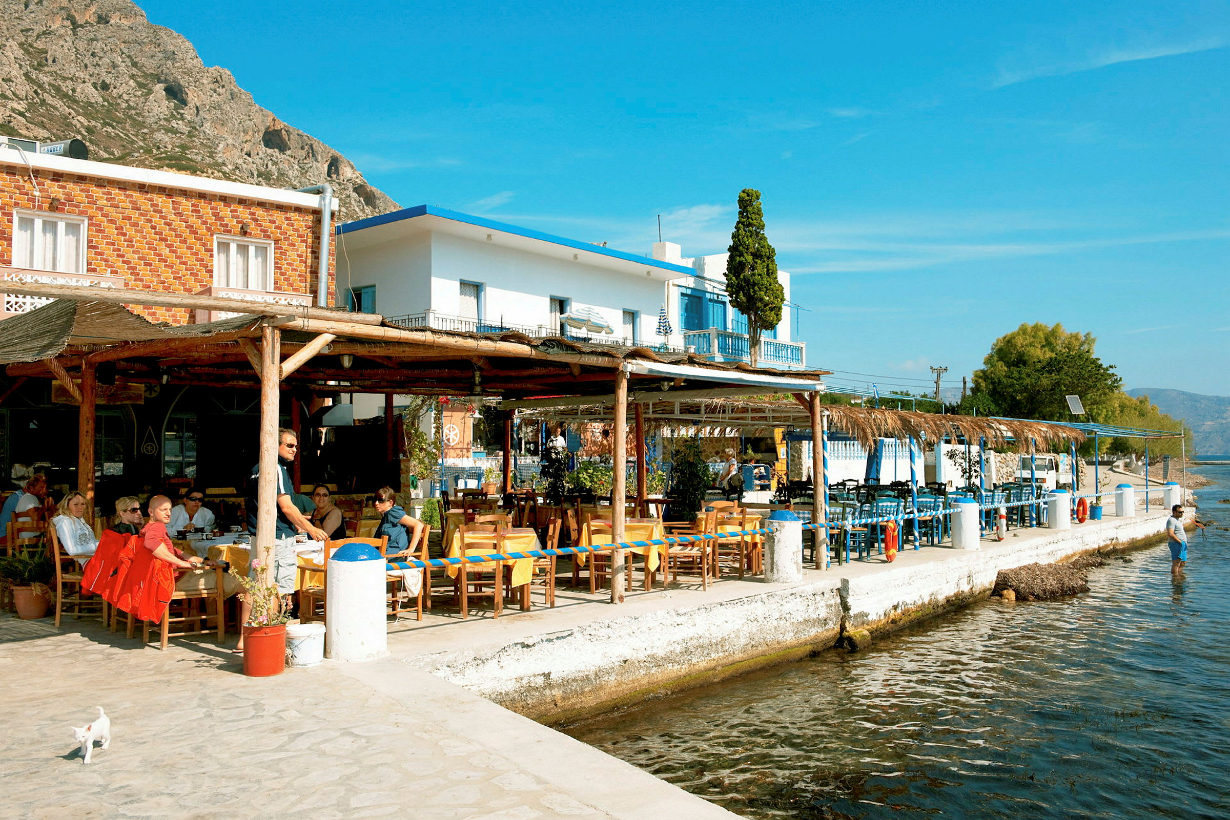 Restaurant ved vandet med borde og siddepladser udendørs. (AI-genereret tekst)