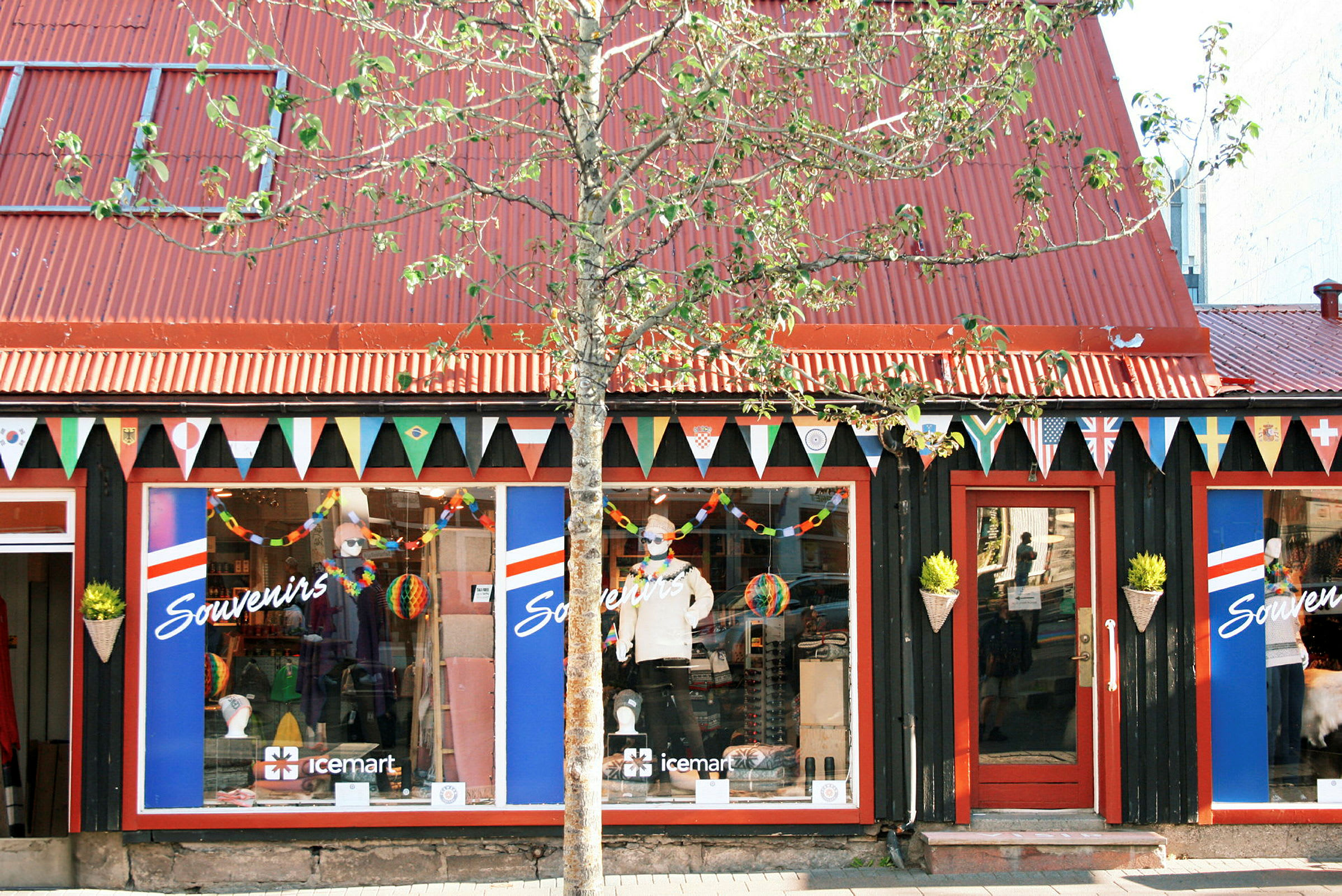 En souvenirbutik med rødt tag og flagguvimpler hængende over udstillingsvinduerne. (AI-genereret tekst)