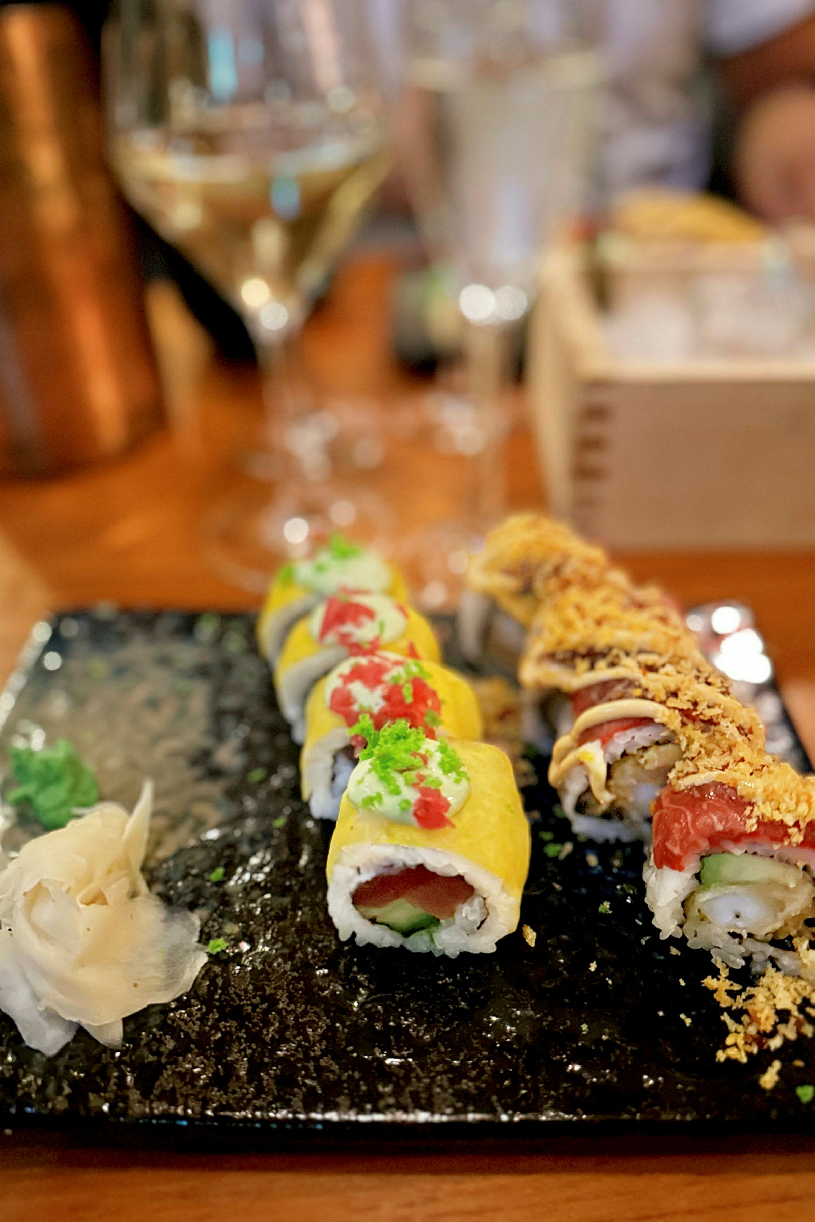 En tallerken med to rækker sushi og tilbehør, serveret på en mørk tallerken. (AI-genereret tekst)