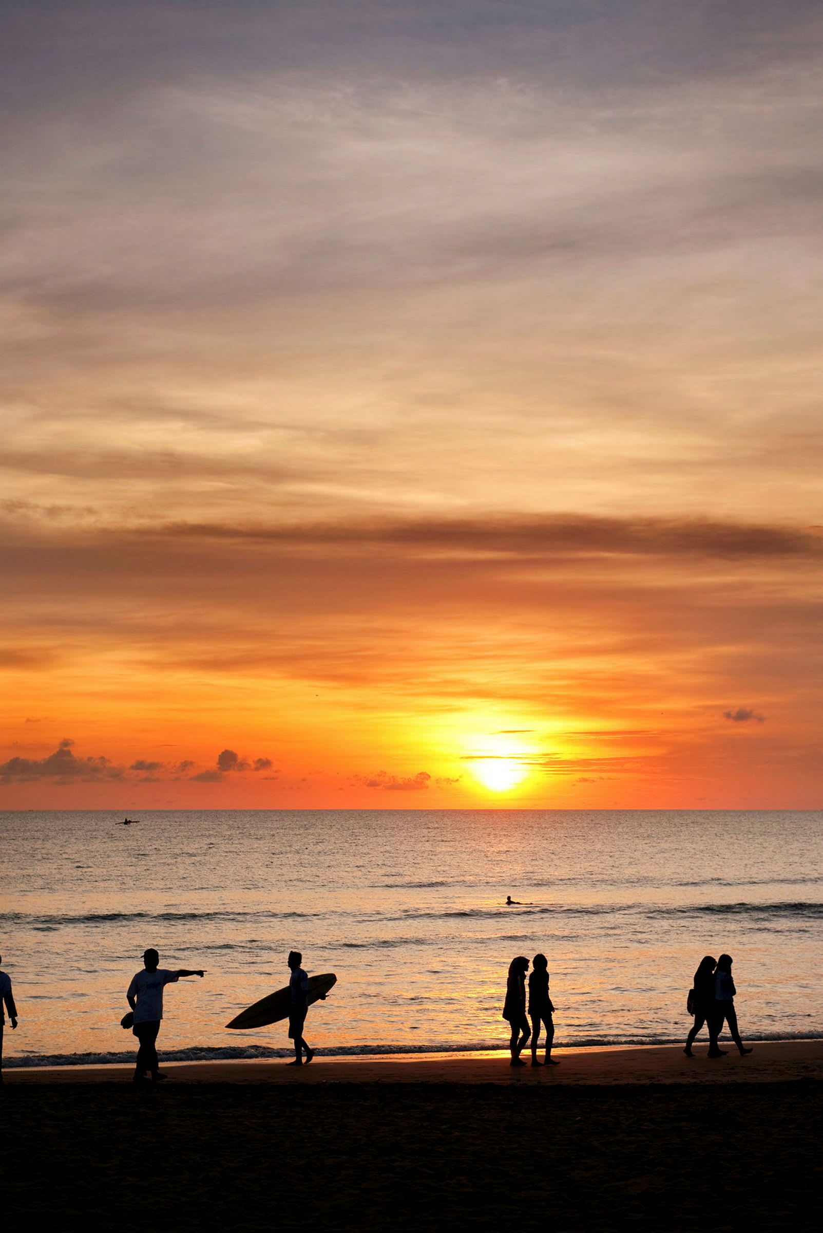 Solnedgang over havet med silhuetter af mennesker på stranden. (AI-genereret tekst)