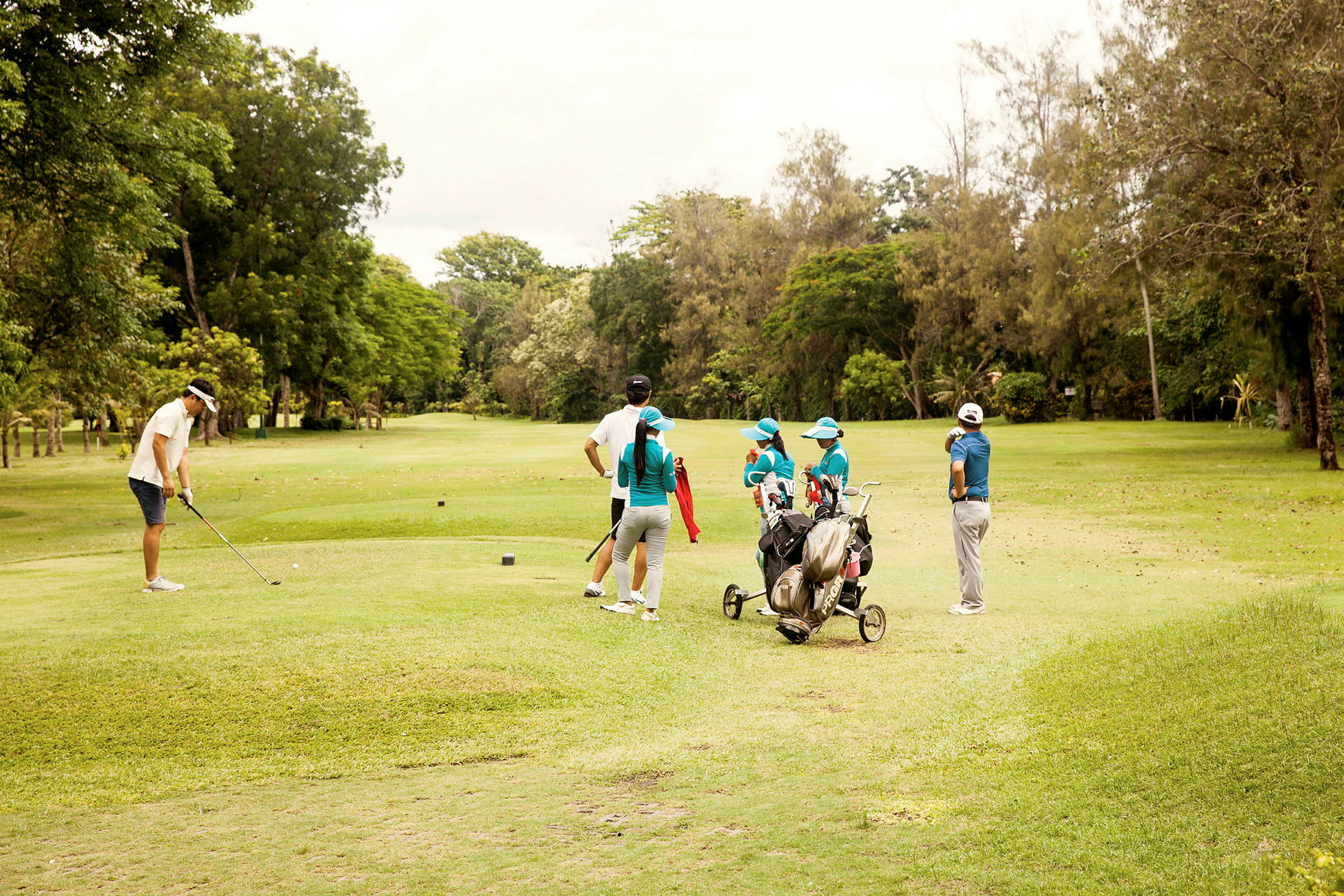 En gruppe mennesker på en grøn golfbane, nogle holder golfkøller. (AI-genereret tekst)
