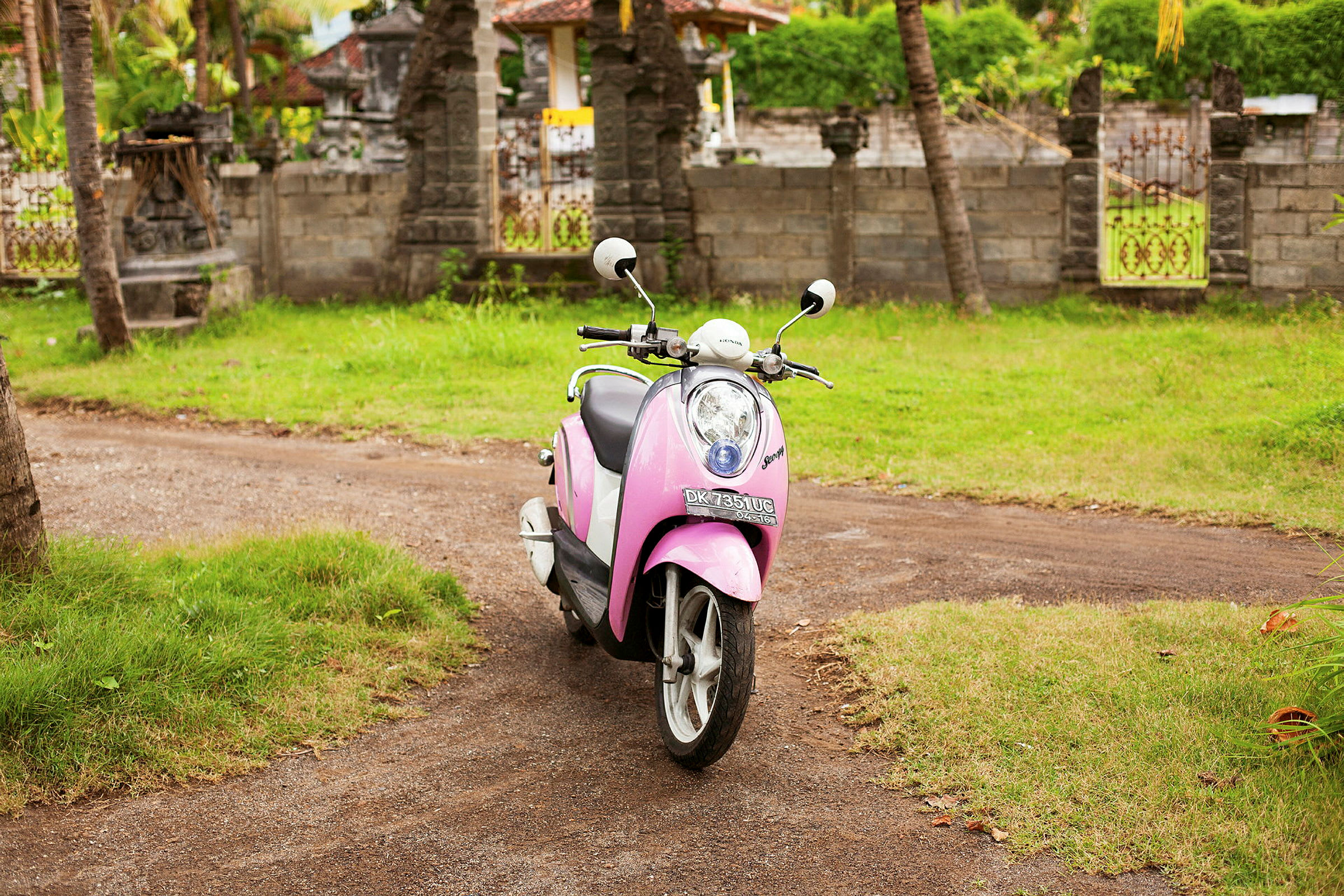 En lyserød scooter står parkeret udendørs på en grusvej. (AI-genereret tekst)