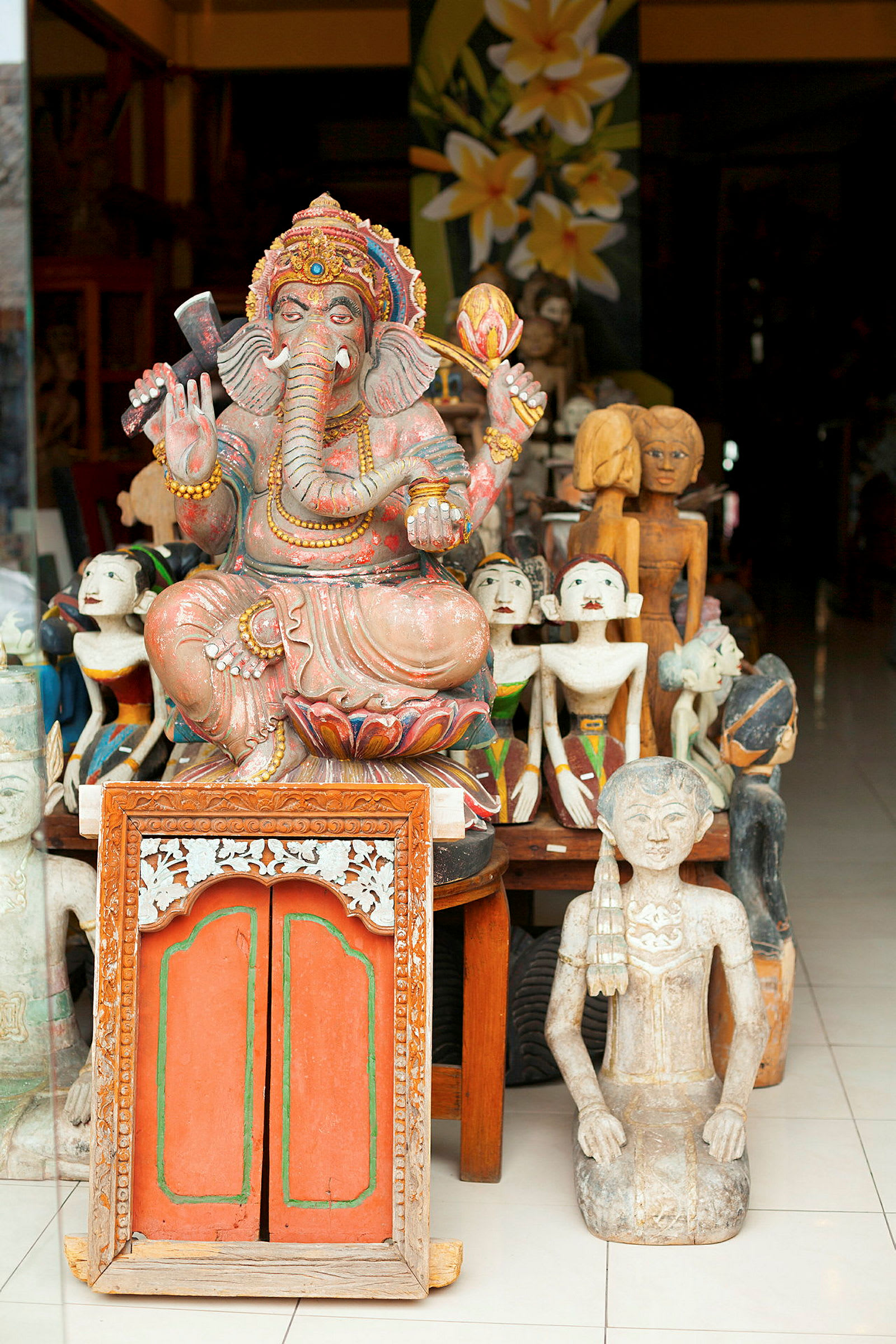 Dekoreret statue af Ganesha og andre skulpturer placeret på en butikshylde. (AI-genereret tekst)
