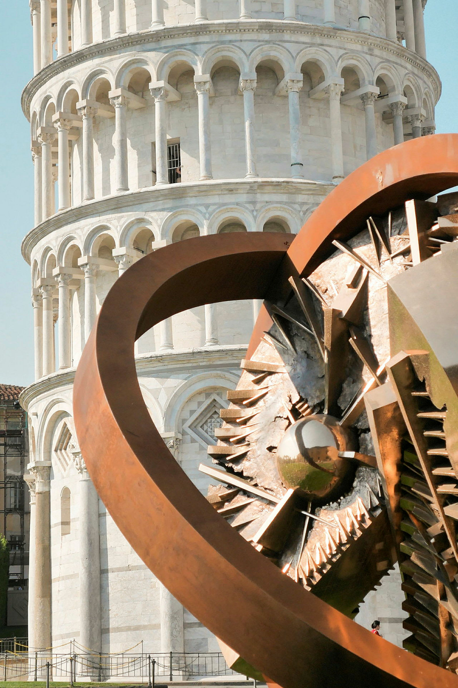 Billede af det skæve tårn i Pisa med en moderne metalskulptur i forgrunden. (AI-genereret tekst)