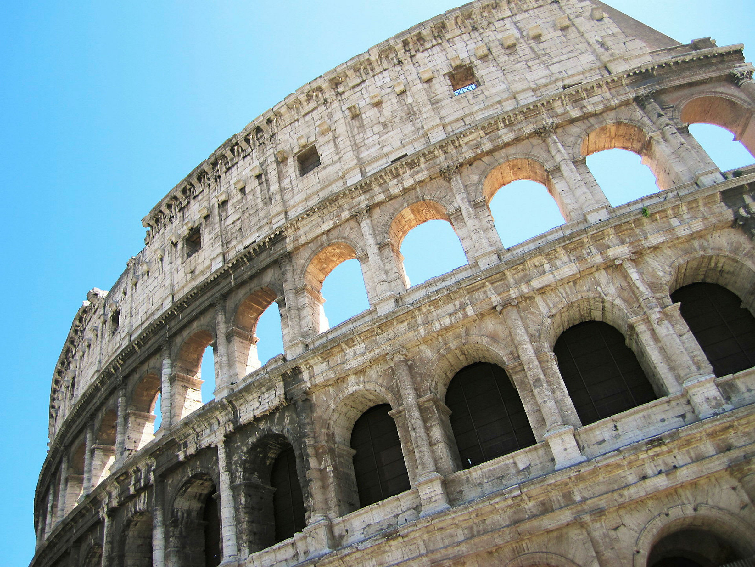 Et fotografi af Colosseum i Rom, Italien, mod en klar blå himmel. (AI-genereret tekst)