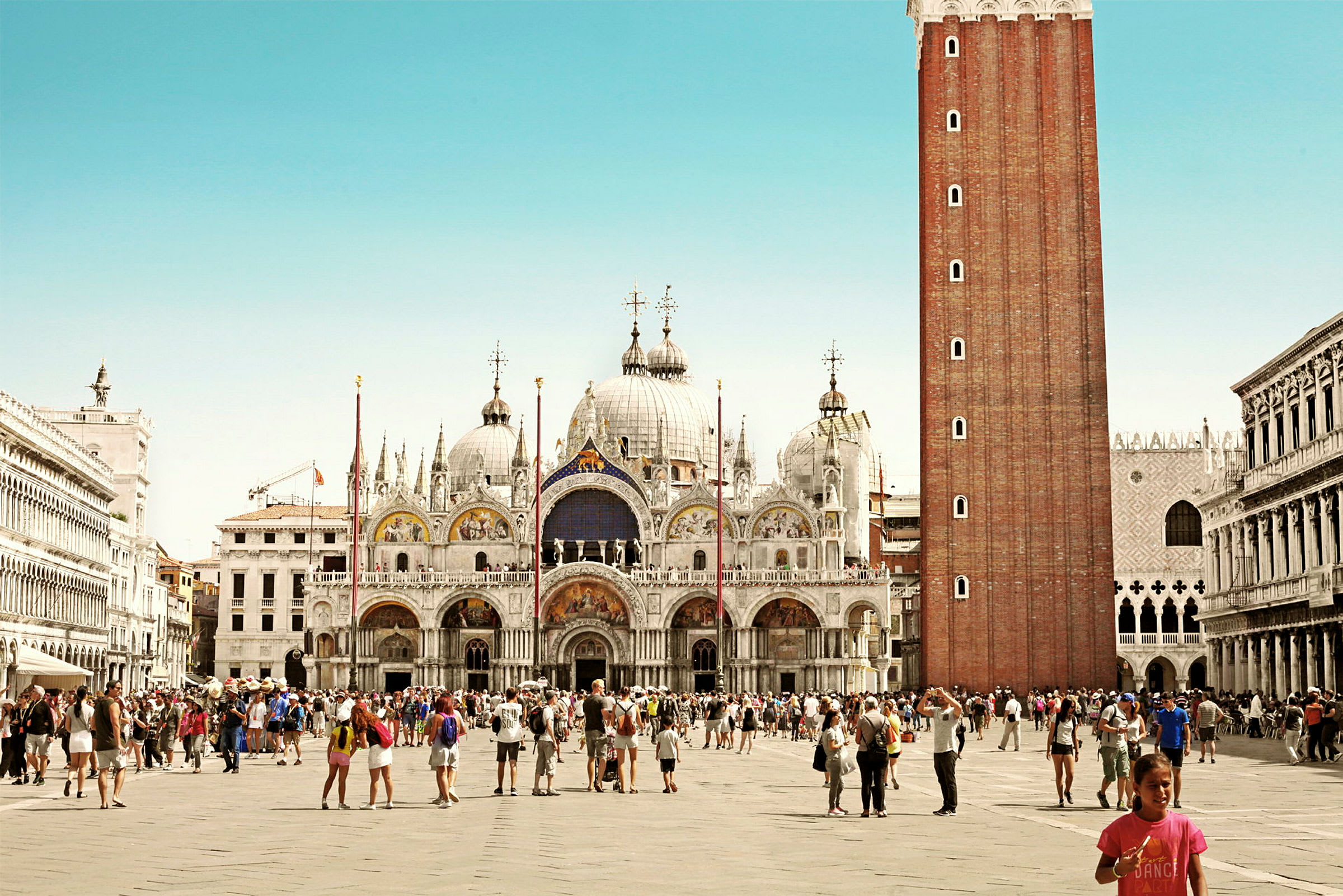 Markuspladsen i Venedig med basilikaen og klokketårnet i baggrunden. (AI-genereret tekst)