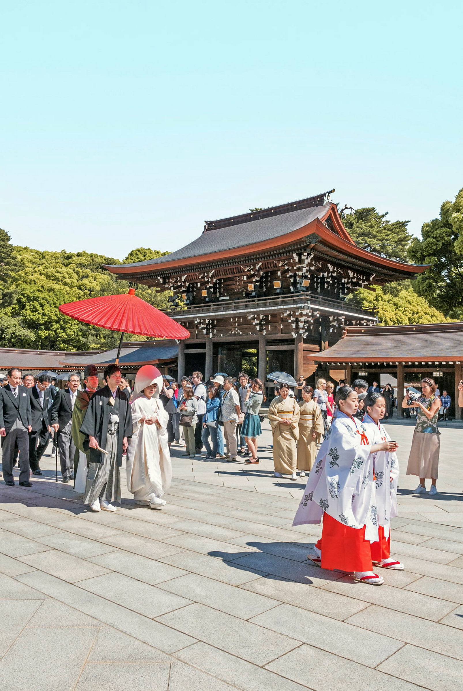 En traditionel ceremoni ved et japansk tempel med personer i traditionelle klæder og en bygning med rødt tag i baggrunden. (AI-genereret tekst)