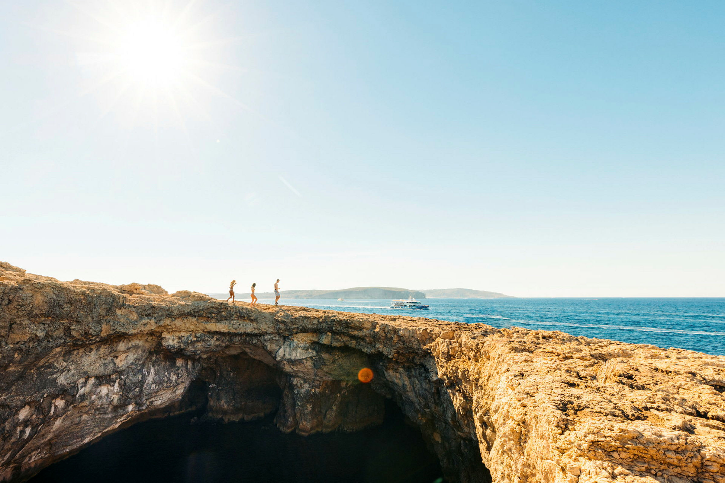 Tre personer går på en klippe med havet i baggrunden. (AI-genereret tekst)