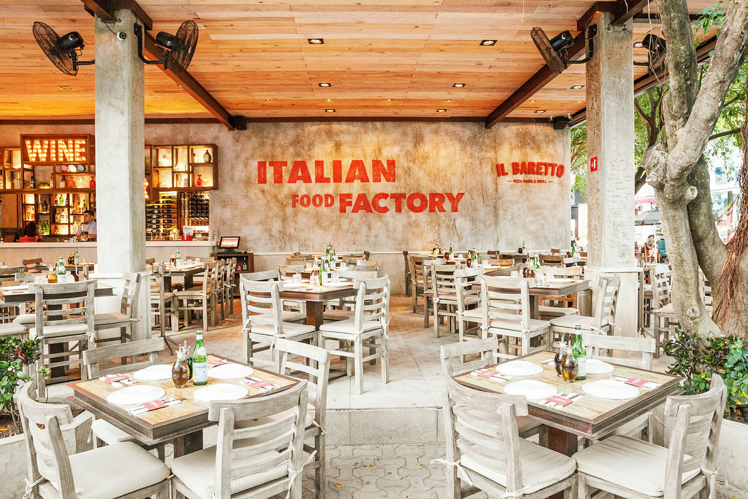 En italiensk restaurant med træborde og -stole, en indbydende atmosfære og et skilt med teksten "Italian Food Factory" på væggen. (AI-genereret tekst)