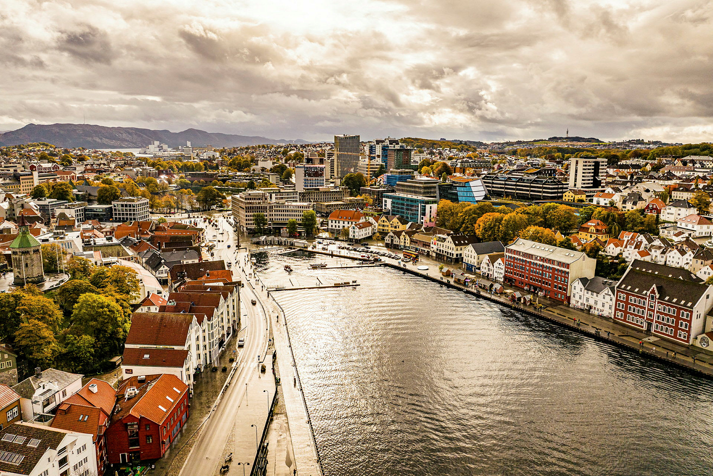 Luftfoto af en by med farverige bygninger langs en vandvej. (AI-genereret tekst)