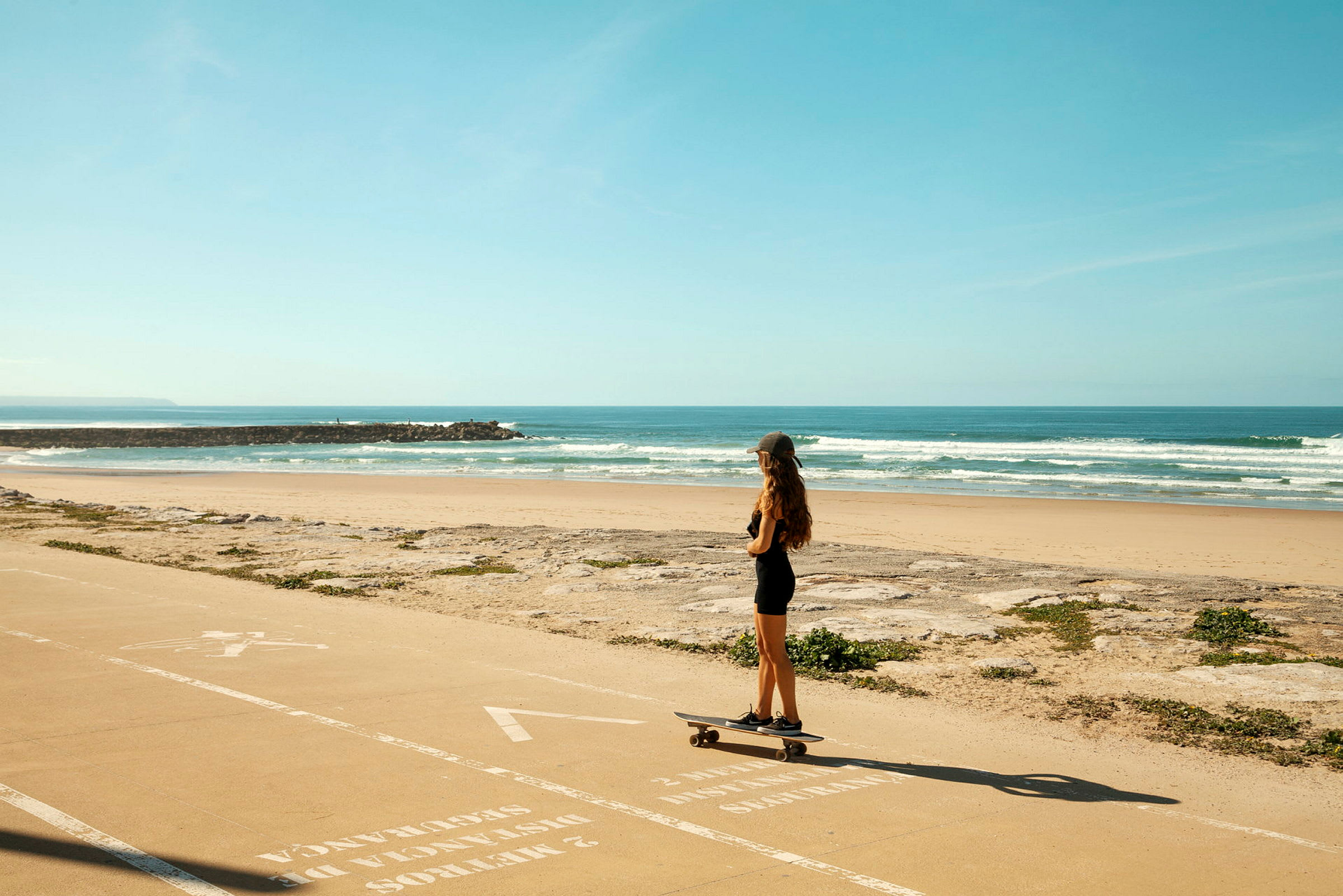 En person står på skateboard på en gangsti ved stranden. (AI-genereret tekst)