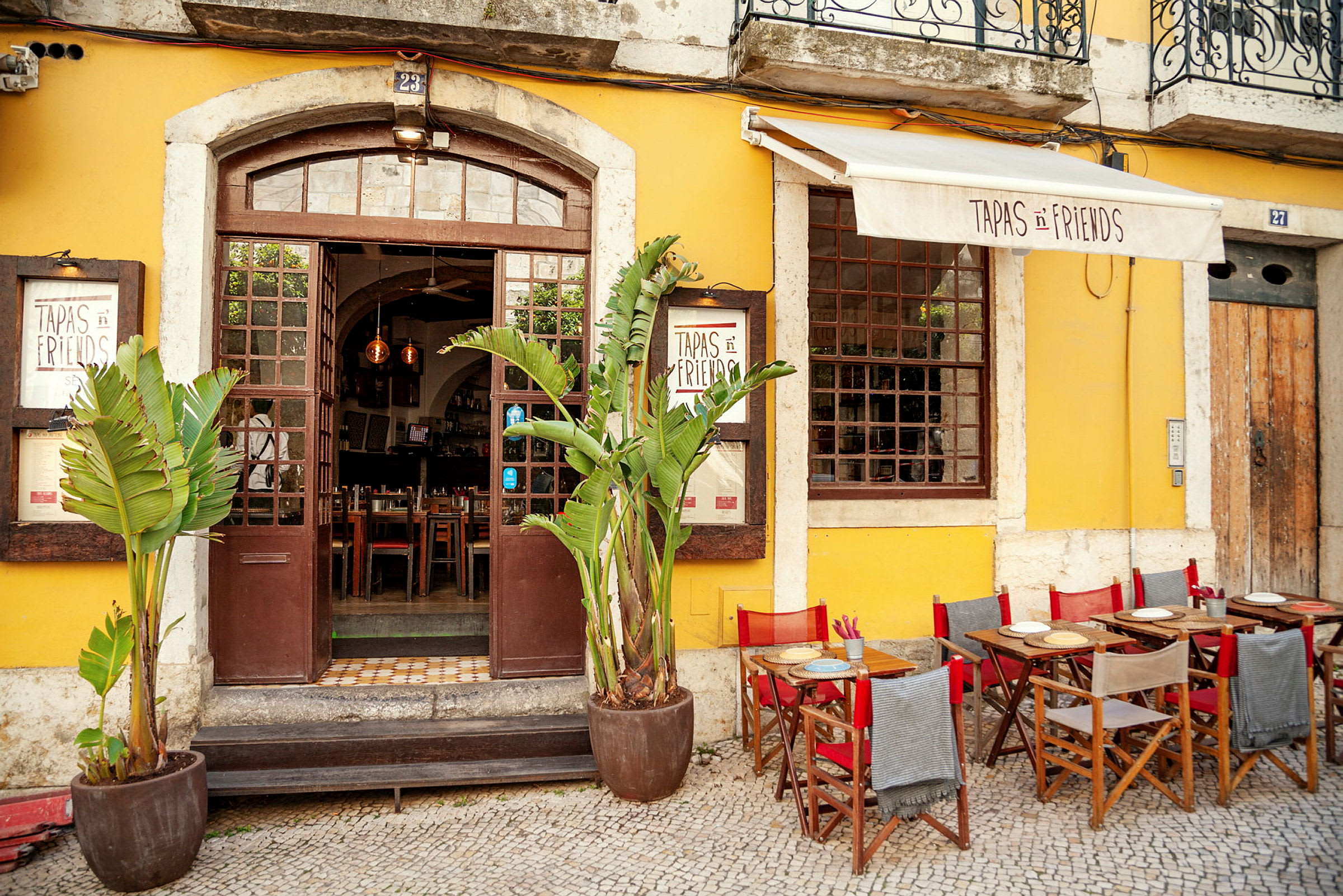 Farverig facade med restaurantindgang og udendørs servering. (AI-genereret tekst)