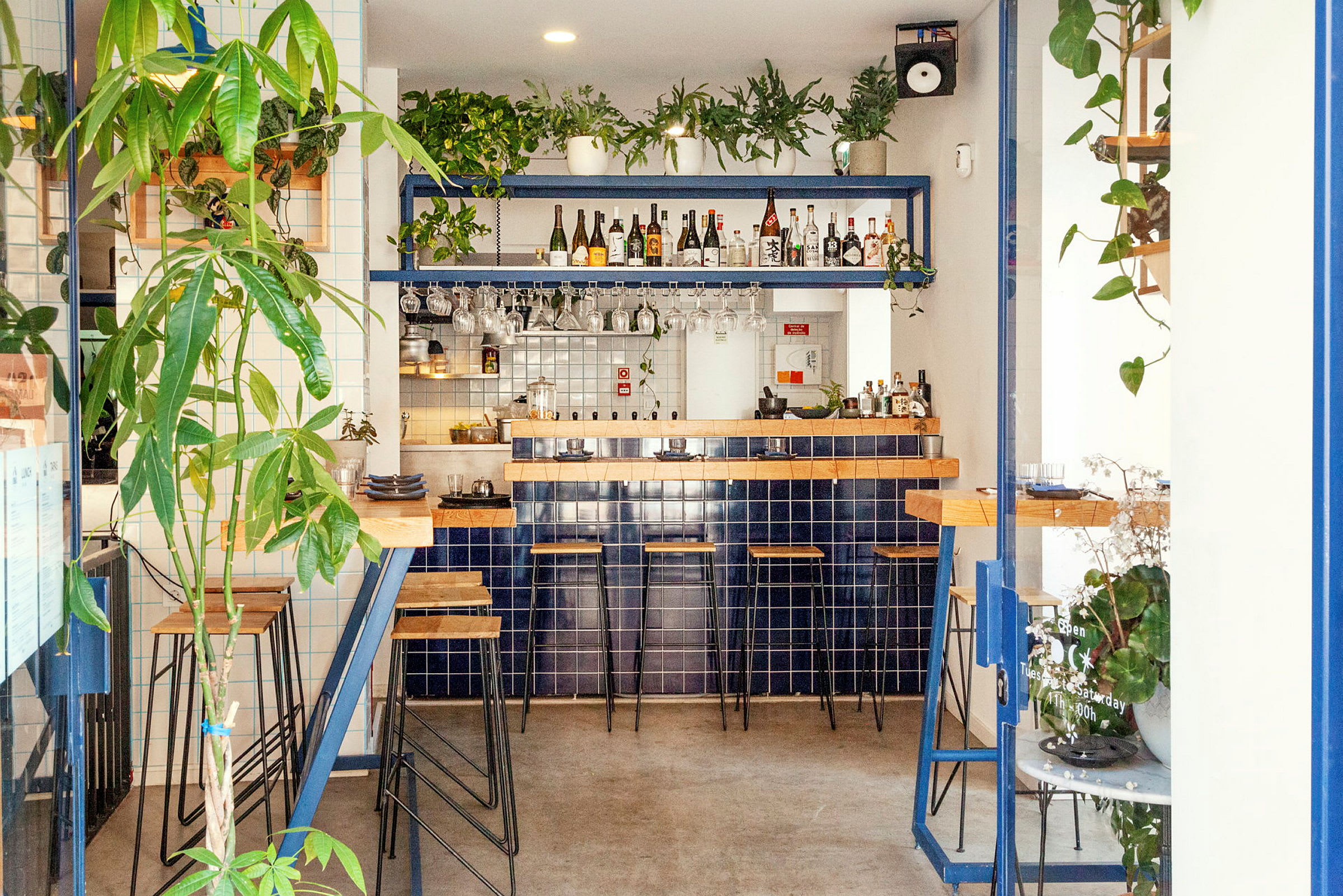 En moderne bar med blå fliser, trædetaljer og grønne planter. (AI-genereret tekst)