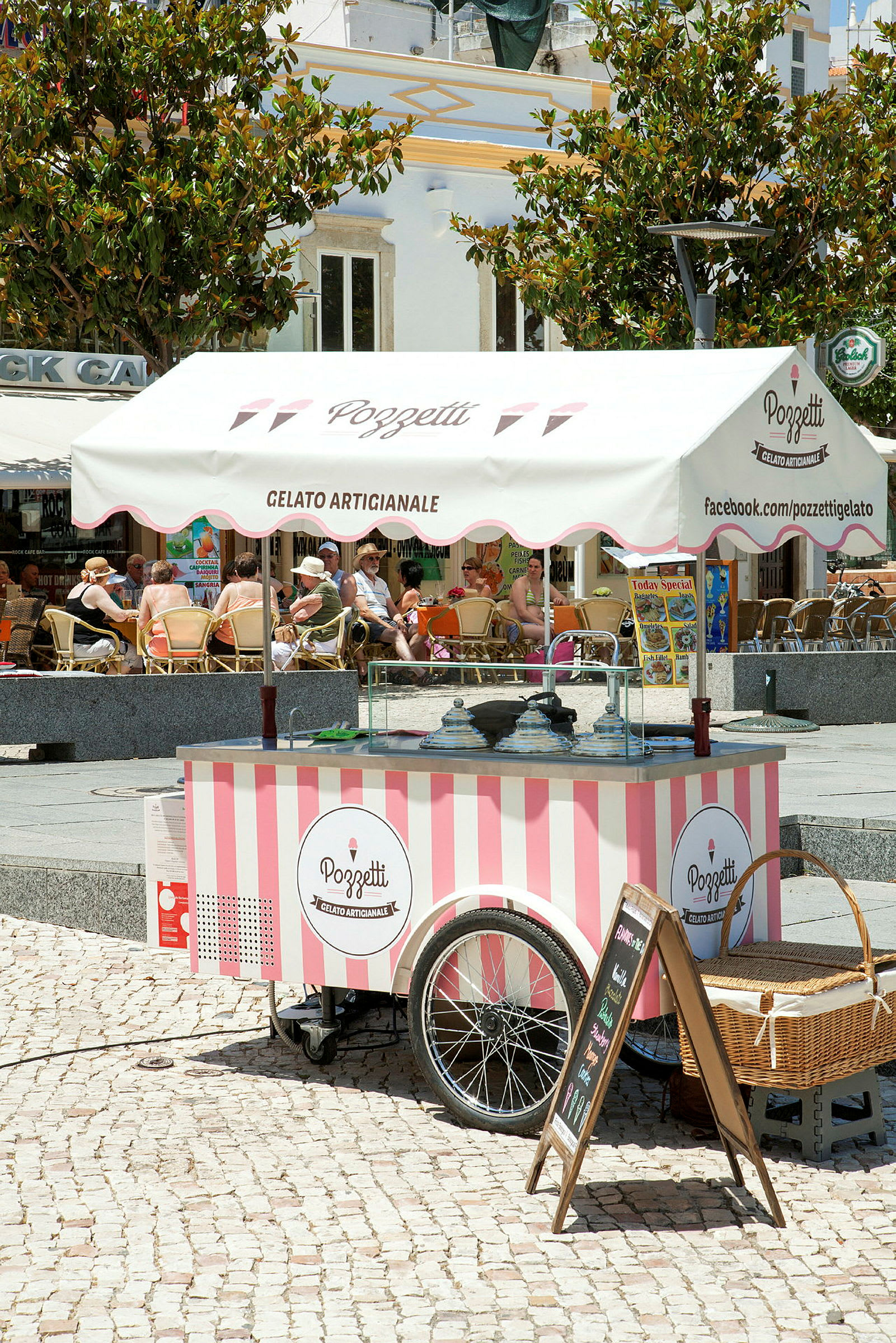 En mobil isbod med lyserøde og hvide striber under en markise med teksten 'Gelato Artigianale'. (AI-genereret tekst)