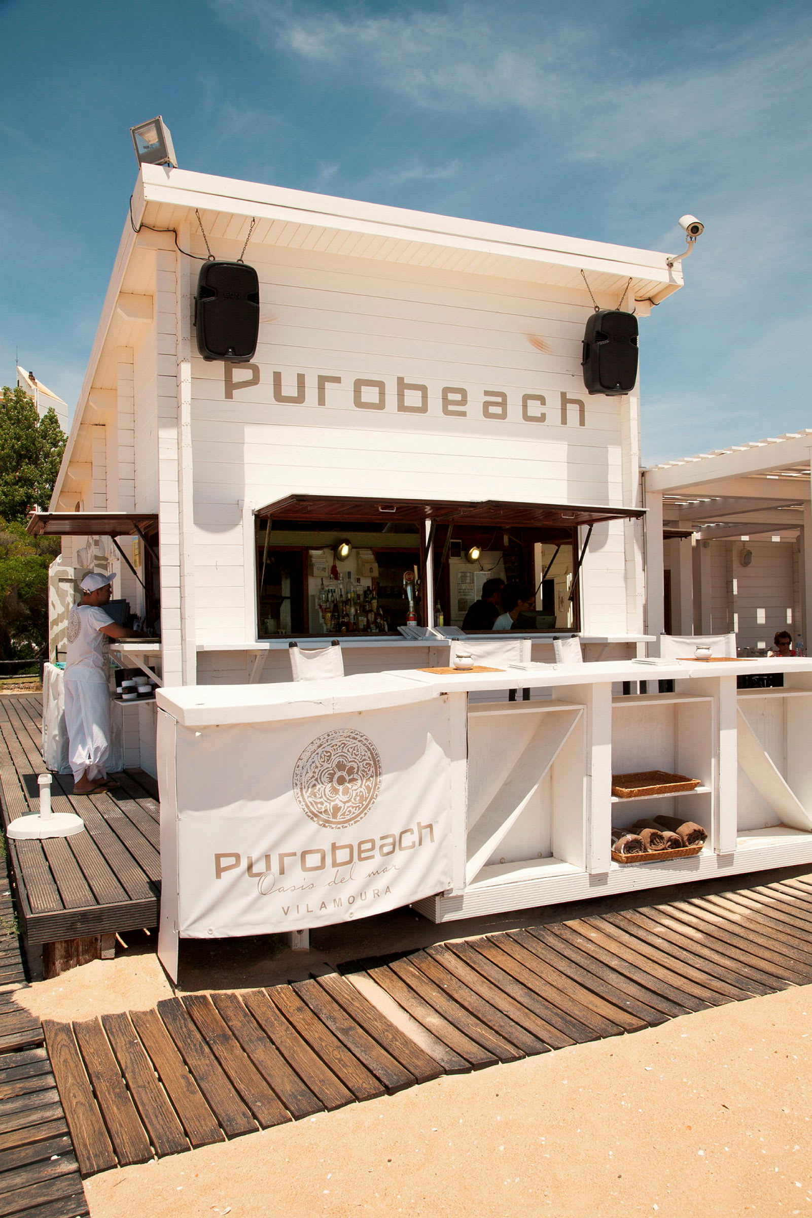 Hvid træbygning med teksten 'Purobeach' på dens front. (AI-genereret tekst)