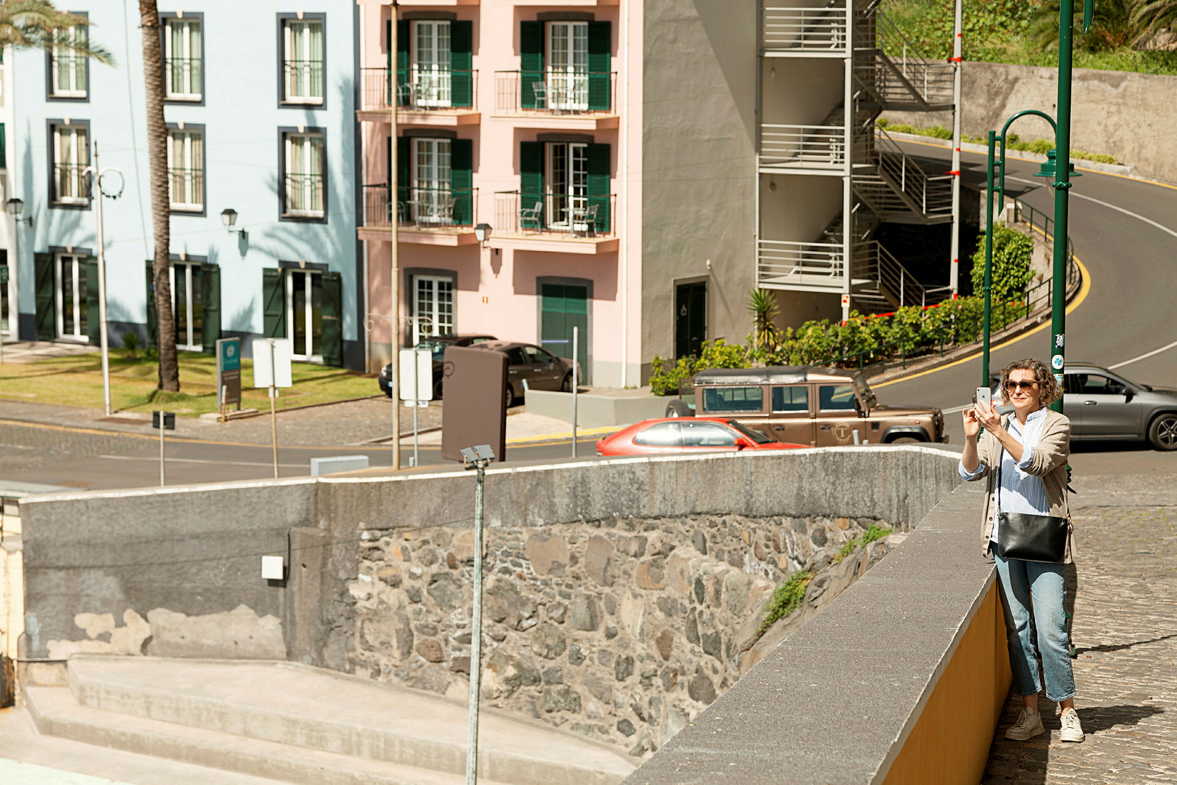 En gade med bygninger i forskellige farver og køretøjer parkeret langs vejen. (AI-genereret tekst)