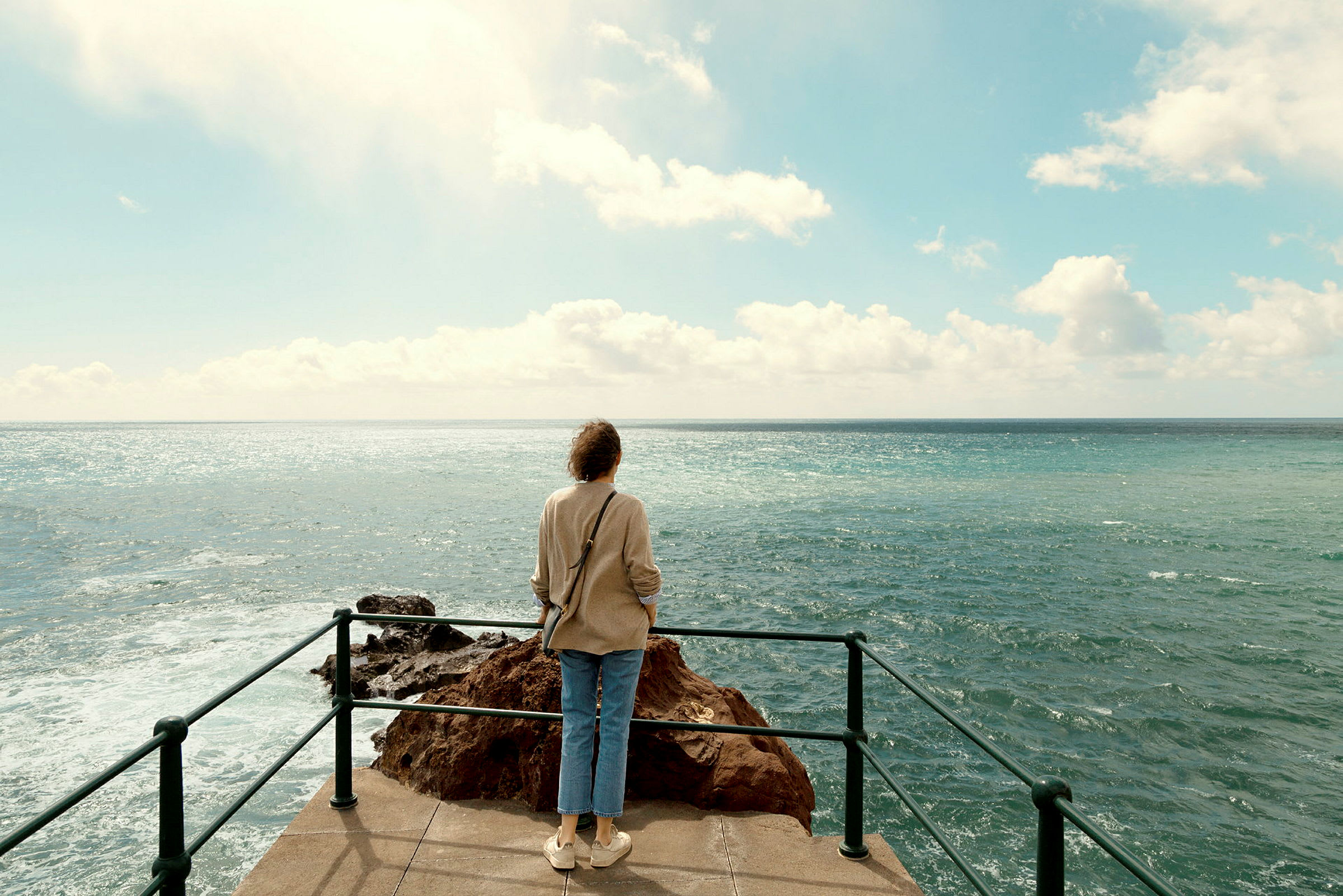En person står på et udsigtspunkt og kigger ud over havet. (AI-genereret tekst)