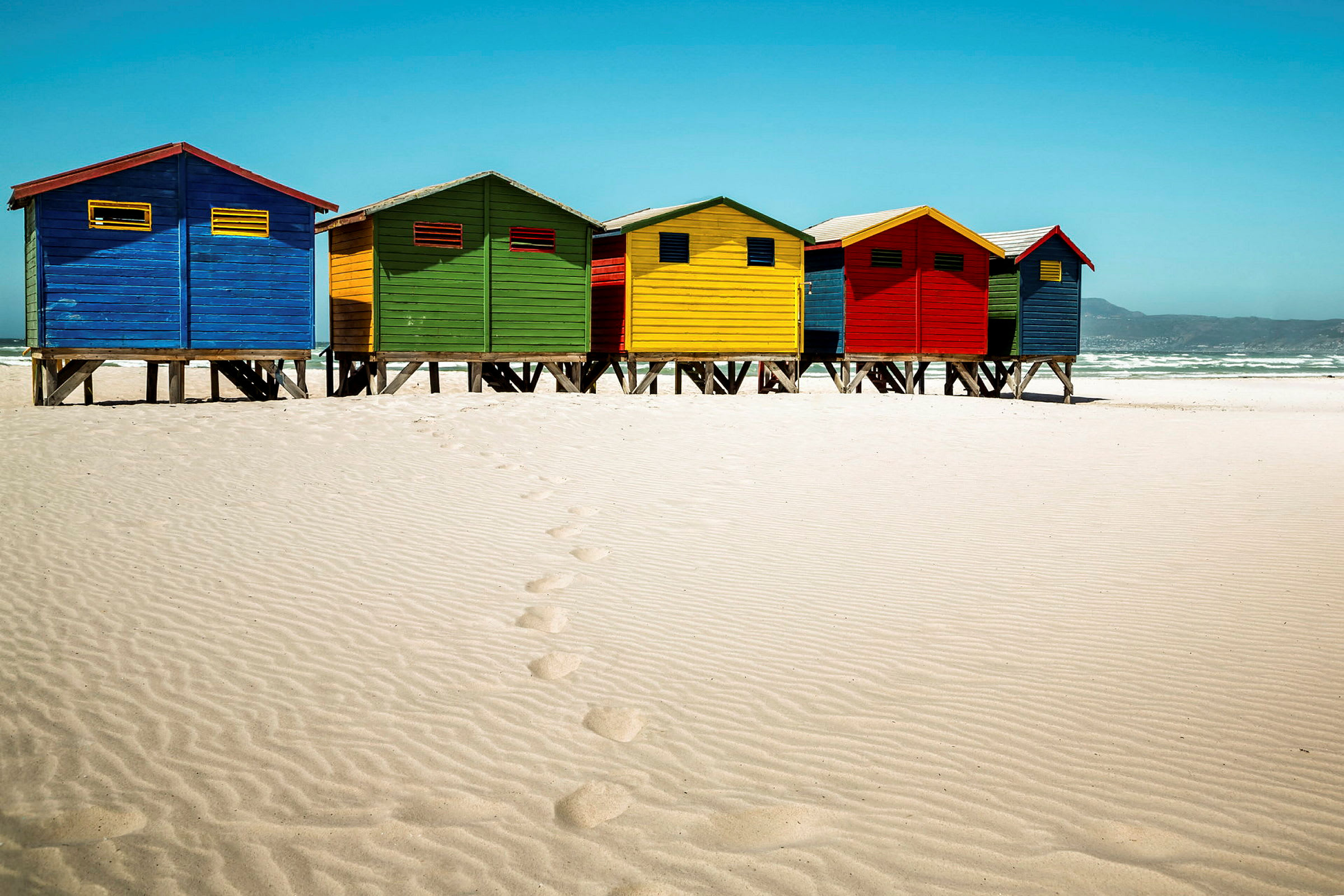 Farverige strandhytter på en sandstrand. (AI-genereret tekst)