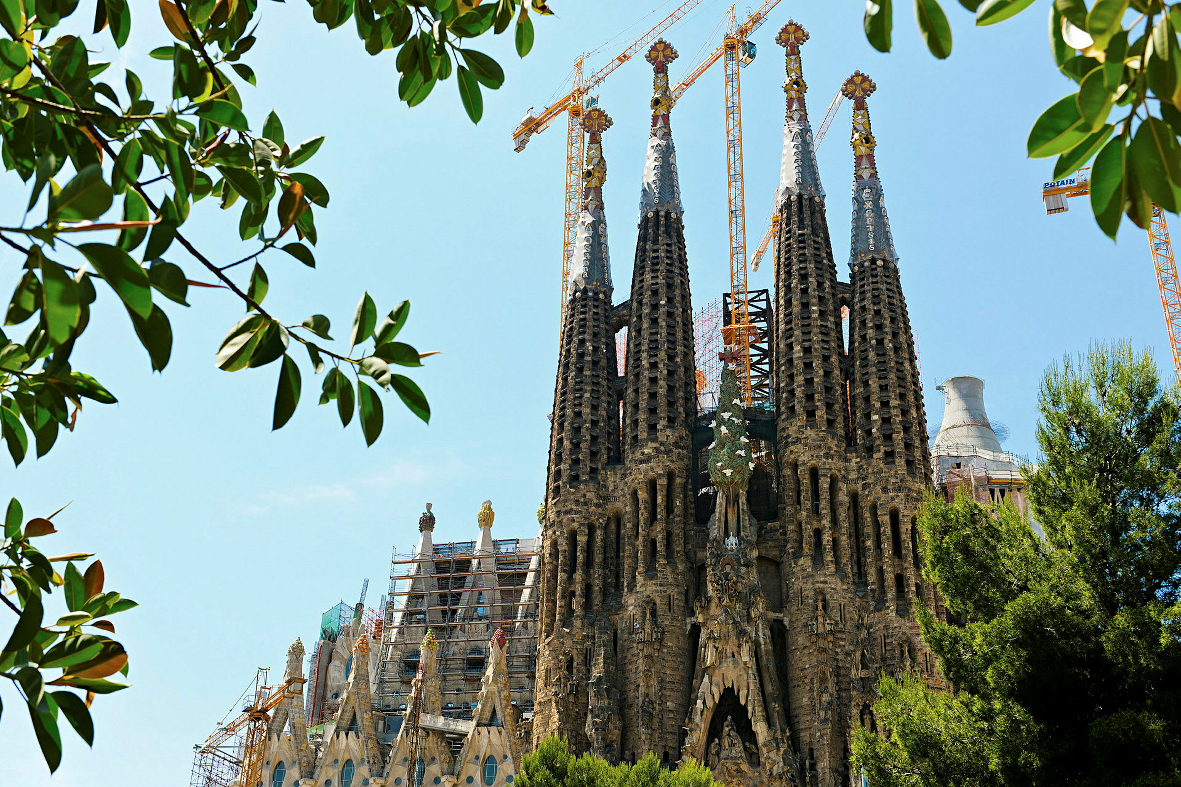 Billede af Sagrada Familia i Spanien, med tårnene synlige gennem trægrene. (AI-genereret tekst)