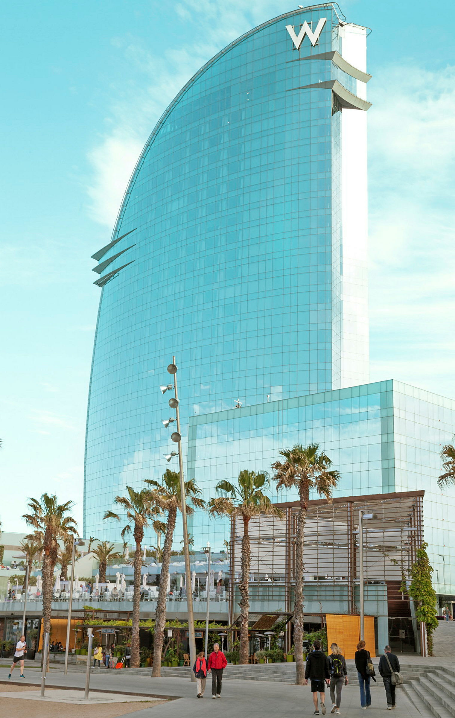 Moderne hotel med glasfacade, omgivet af palmer og gangsti. (AI-genereret tekst)