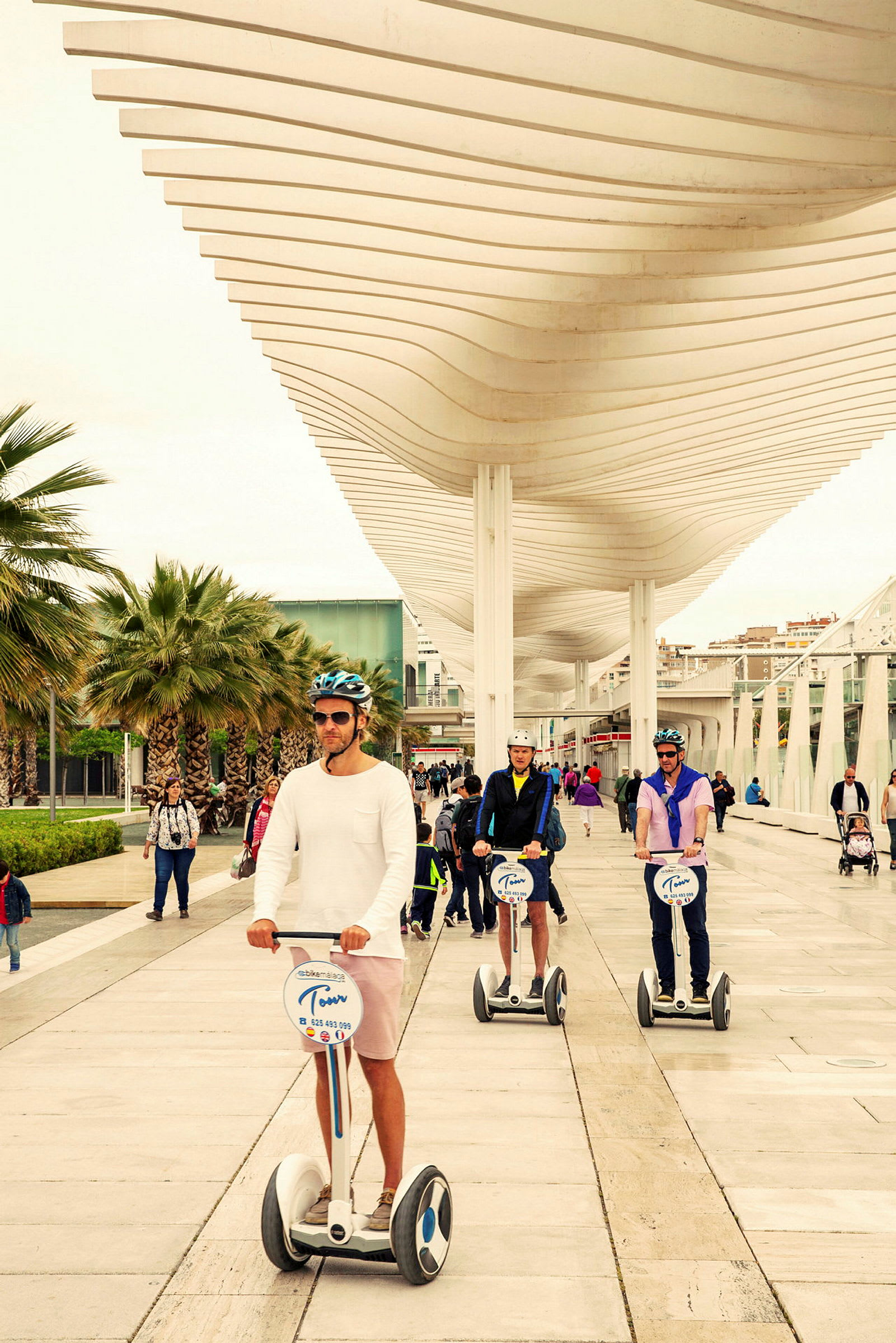 Personer, der kører segways på en promenade under en moderne baldakin. (AI-genereret tekst)