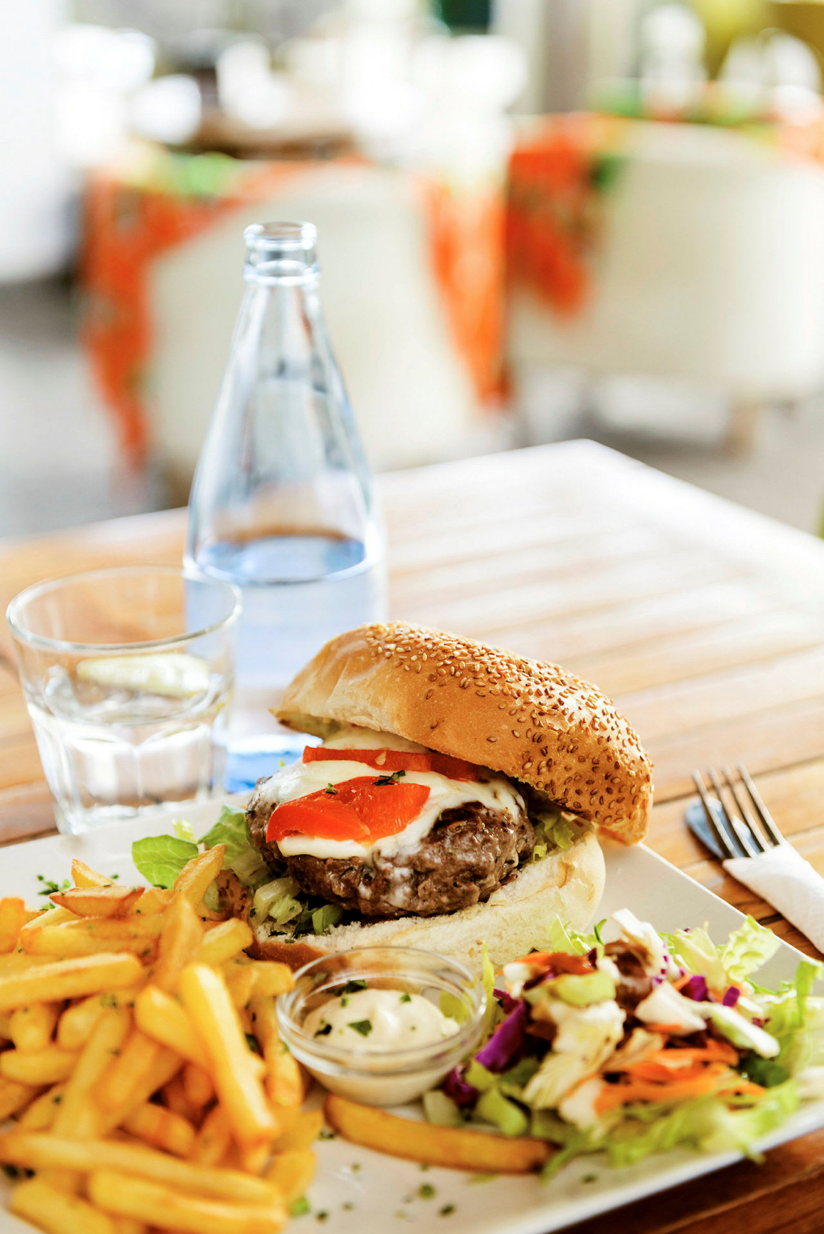 Tallerken med burger, pommes frites, salat og dip serveret på et træbord. (AI-genereret tekst)