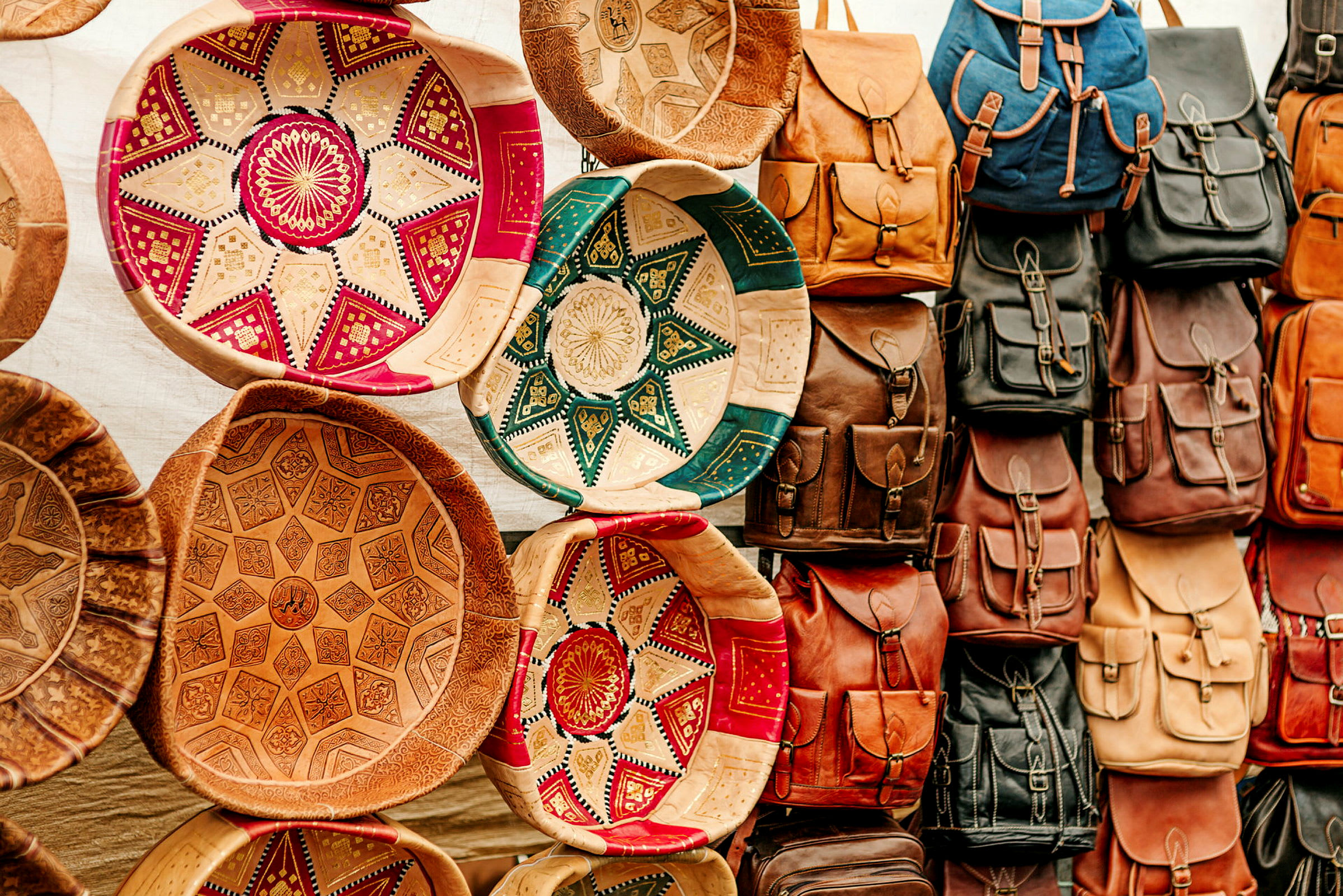 Nærbillede af farverige skåle med mønstre ved siden af hængende rygsække. (AI-genereret tekst)