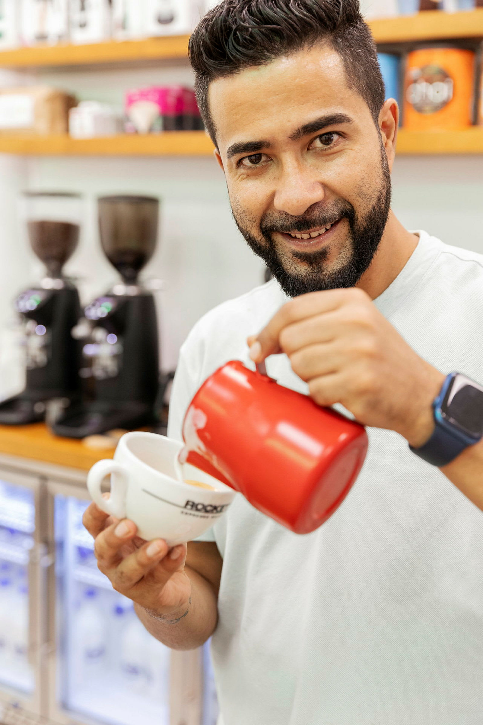 Person hælder mælk i en kaffekop med en rød kande. (AI-genereret tekst)