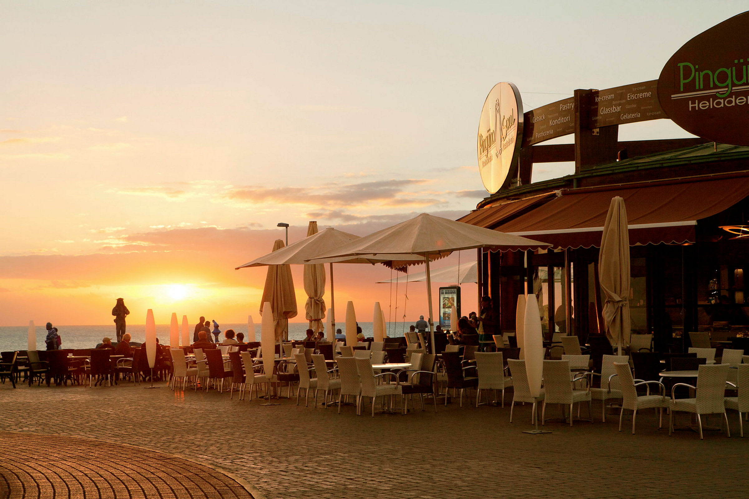 Udendørs siddeplads ved en restaurant ved solnedgang. (AI-genereret tekst)