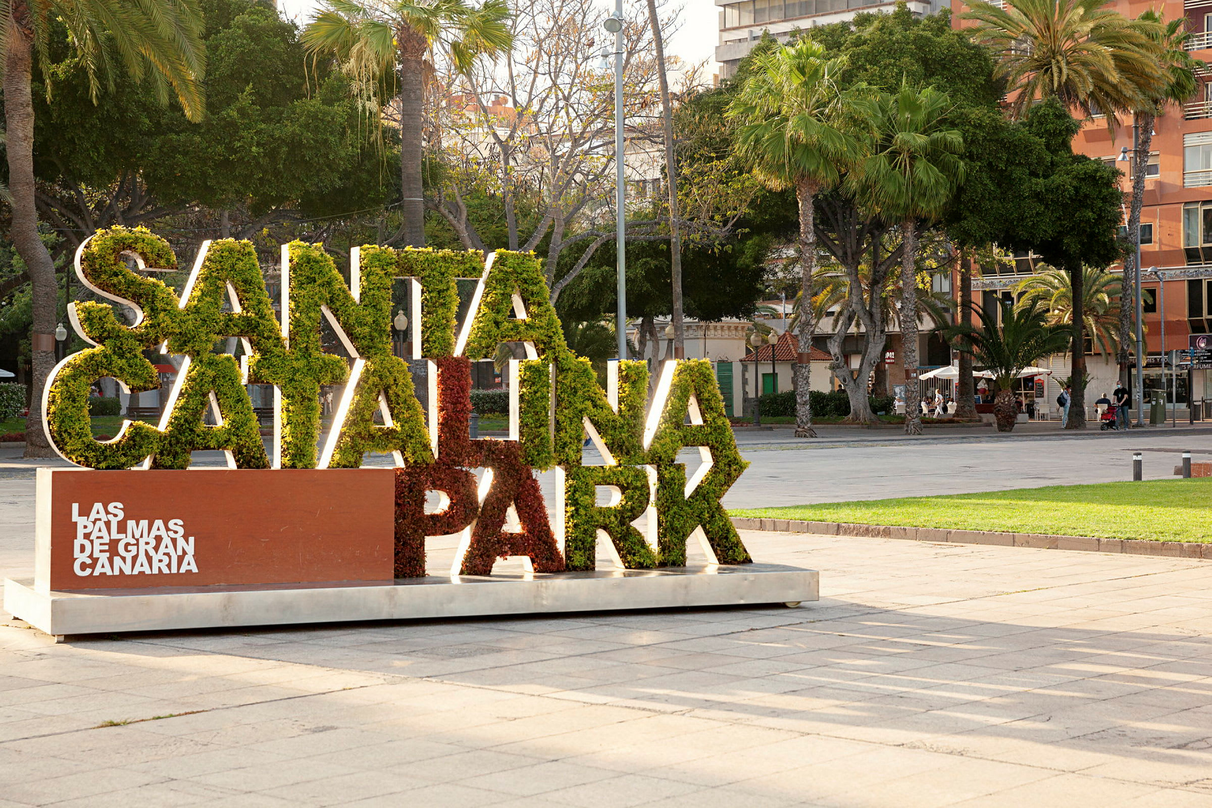 Skilt med teksten 'Santa Catalina Park' fyldt med grønt, omgivet af træer i bypark. (AI-genereret tekst)