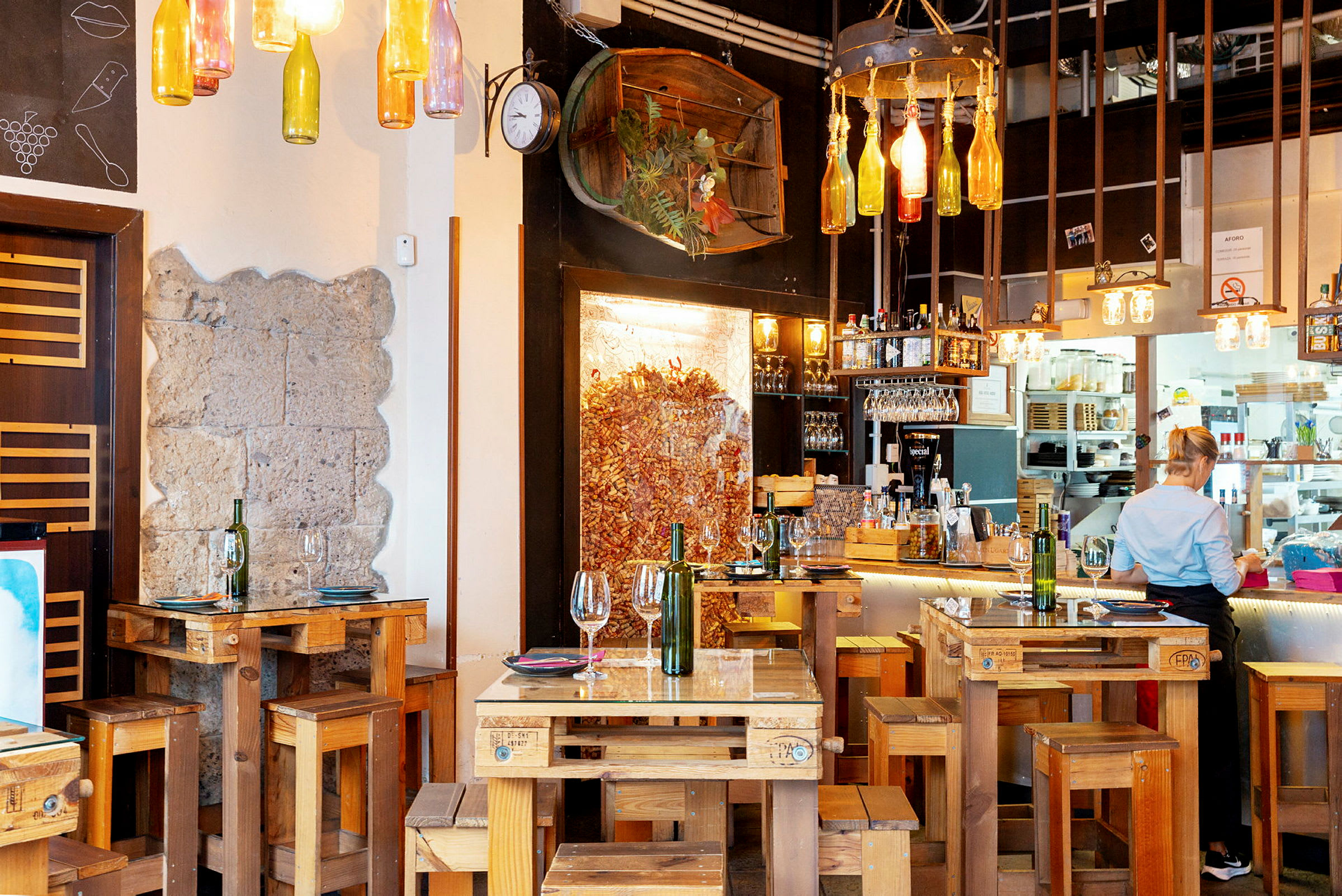 Restaurant med rustikke træmøbler og dekorative flasker hængende fra loftet. (AI-genereret tekst)