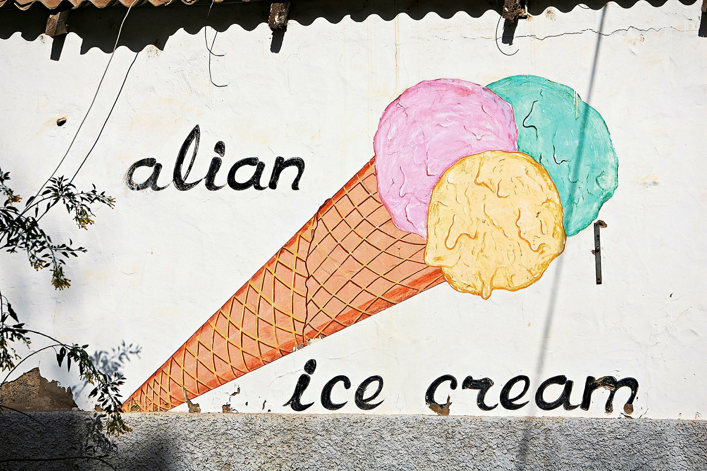Maleri af en isvaffel med tre farverige kugler på en væg med teksten 'alian ice cream'. (AI-genereret tekst)