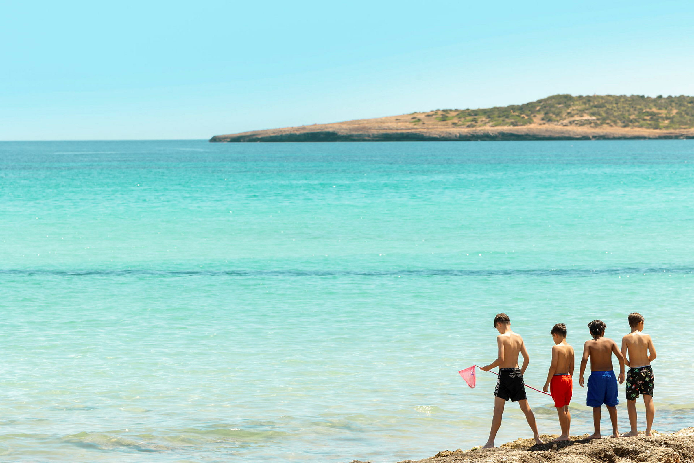 Fire børn står på stranden og kigger ud over havet. (AI-genereret tekst)