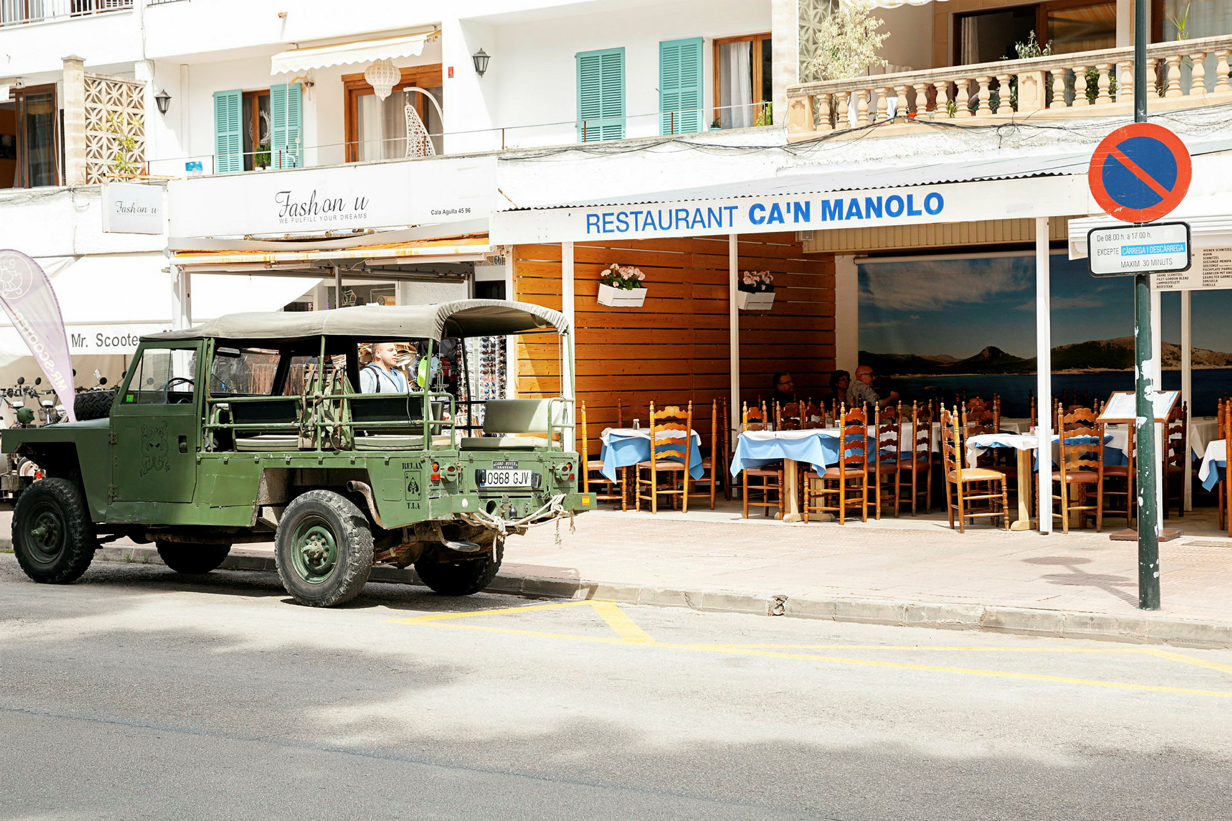 En grøn militær jeep parkeret foran restauranten Can Manolo. (AI-genereret tekst)
