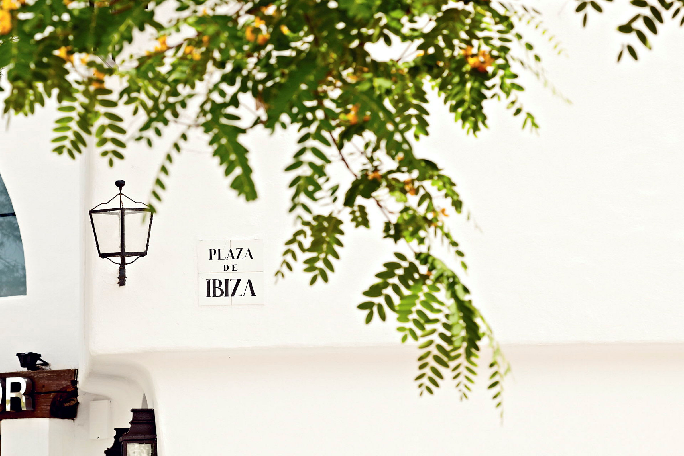 En væg med en lampe og et skilt med teksten 'Plaza De Ibiza'. (AI-genereret tekst)